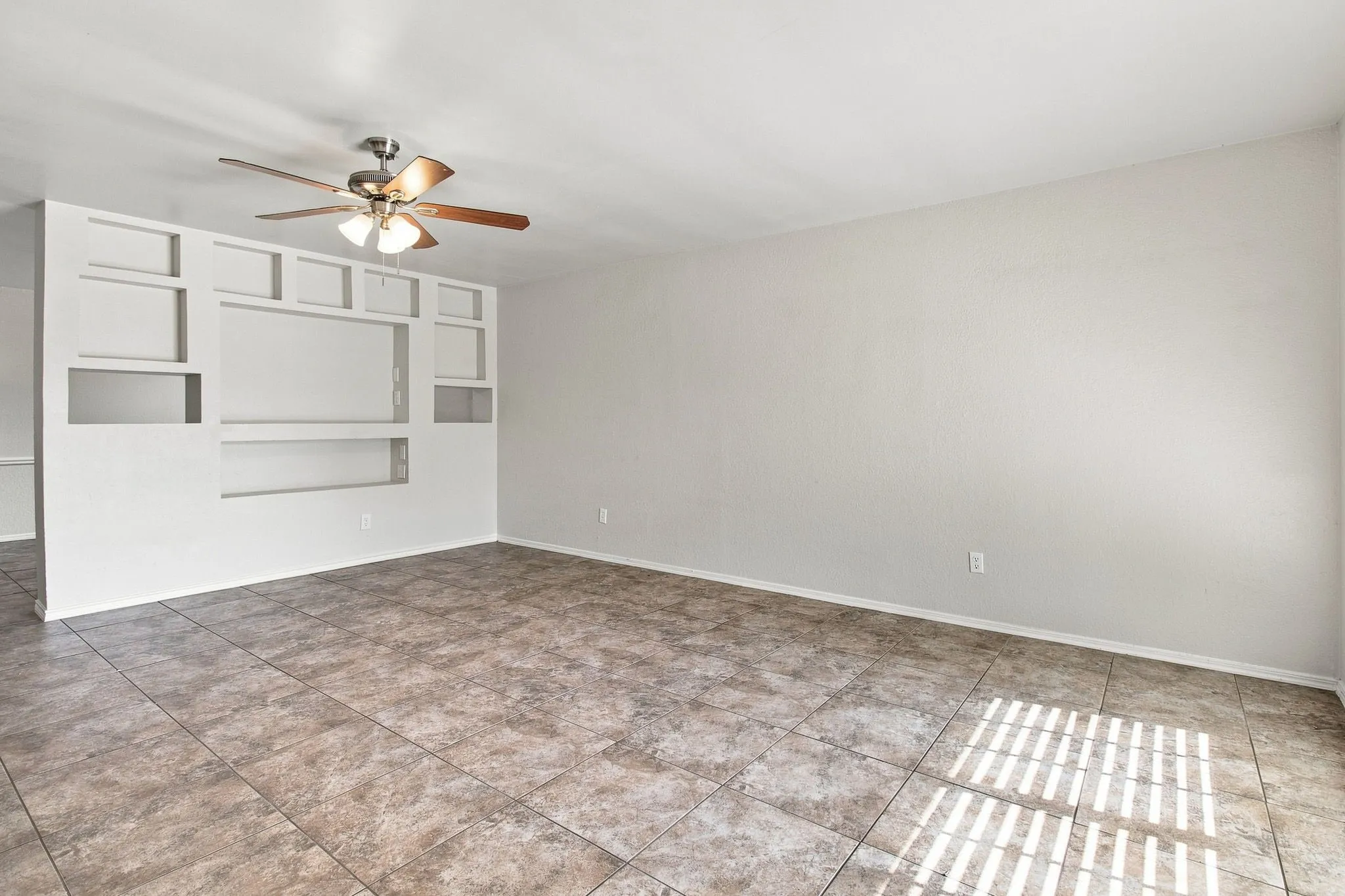 Tiled flooring with a neutral finish, built-in wall niches, and a ceiling fan with light fixture