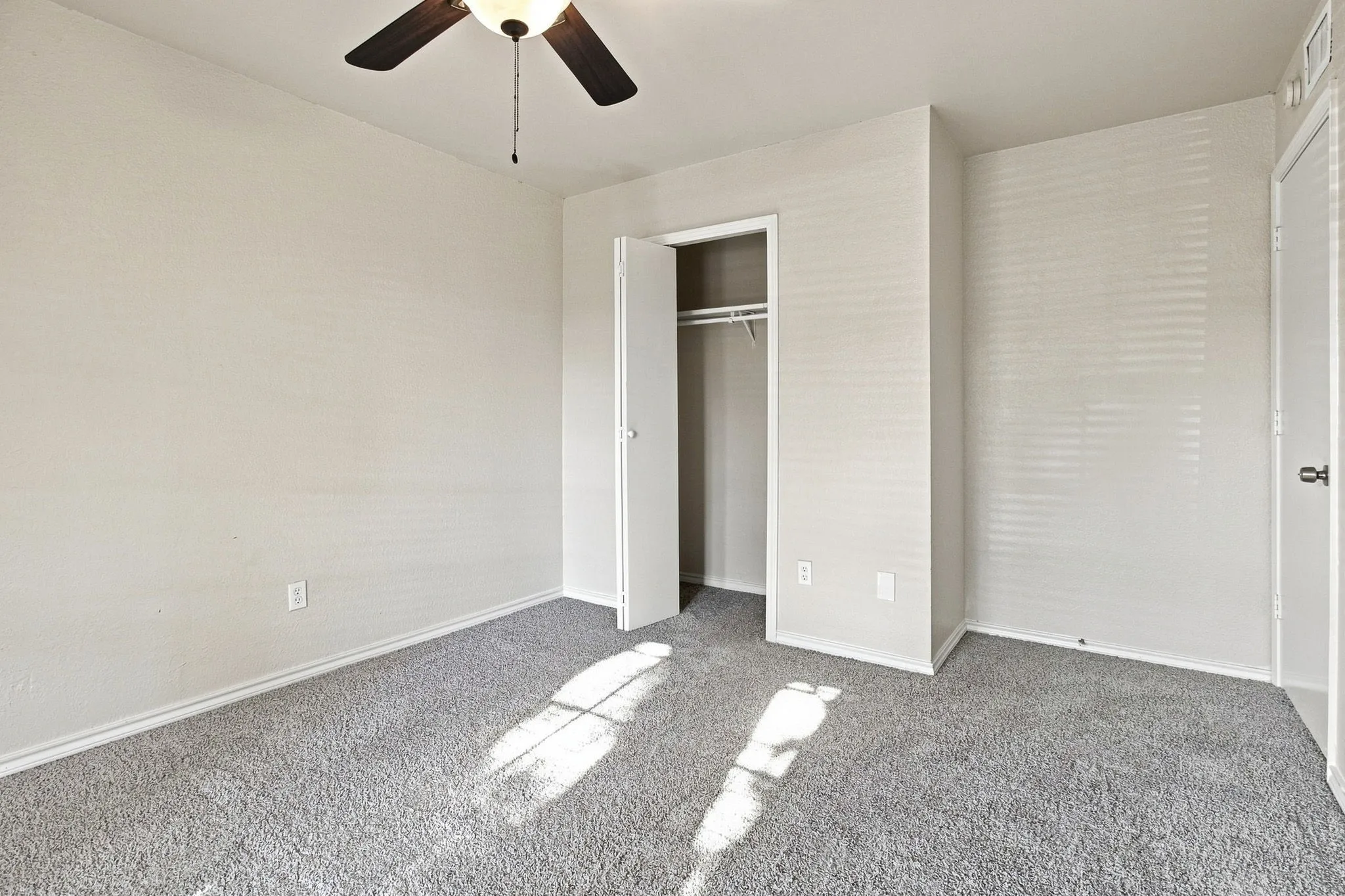 Neutral toned walls, gray carpet, ceiling fan with integrated lighting, and built-in closet with hanging rod