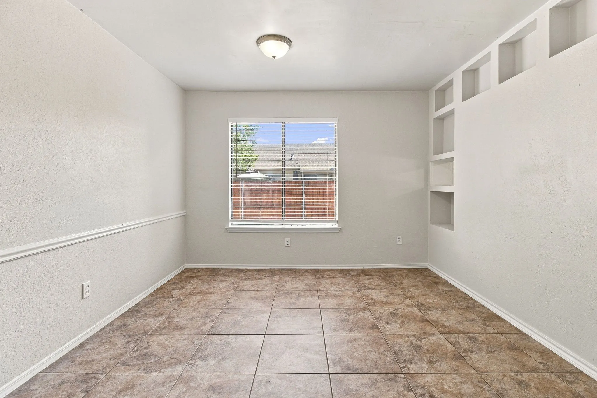 Recessed wall shelving, window with blinds, tile flooring, and decorative wall molding