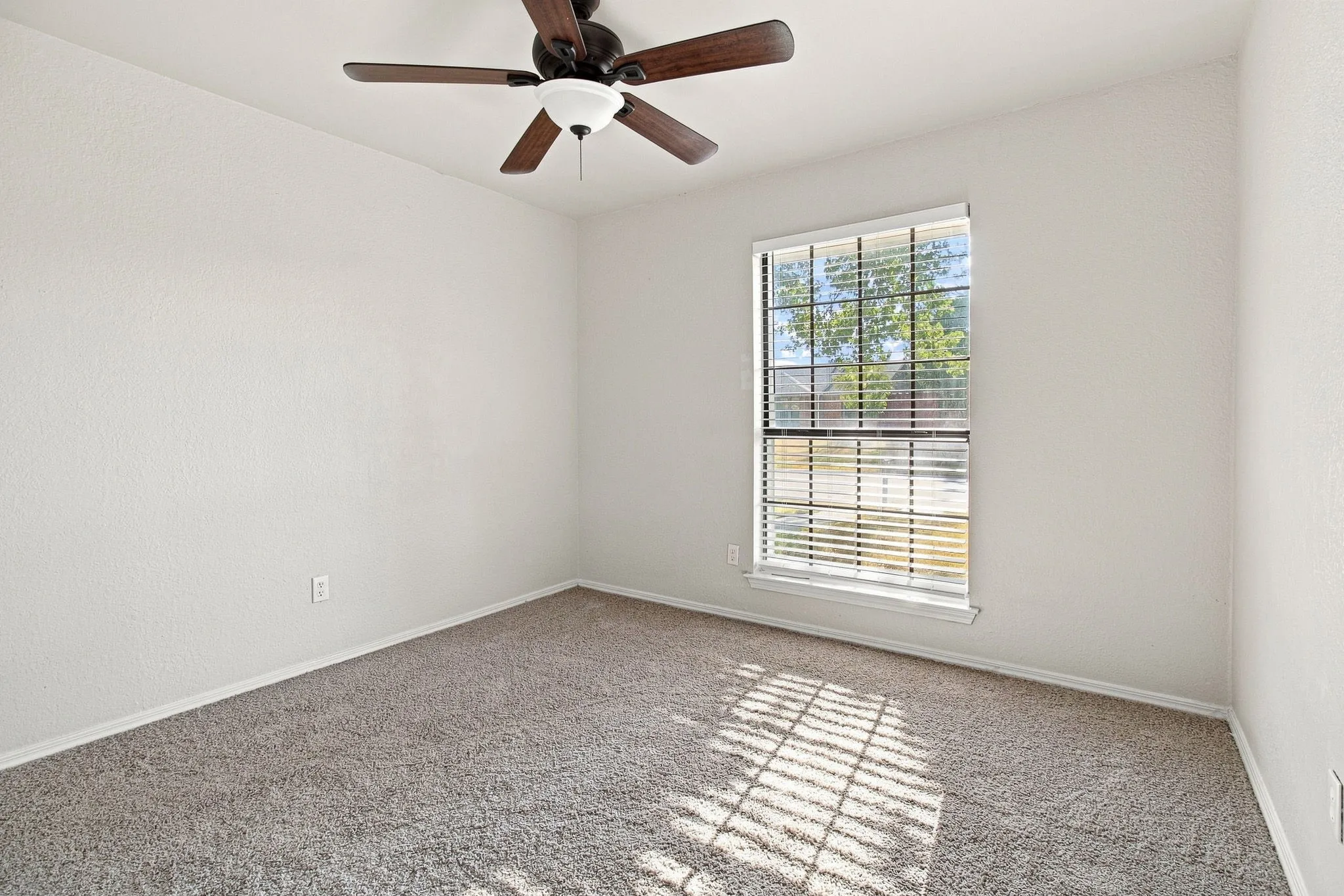 Neutral wall paint with textured finish, carpeted flooring, and a ceiling fan with integrated lighting