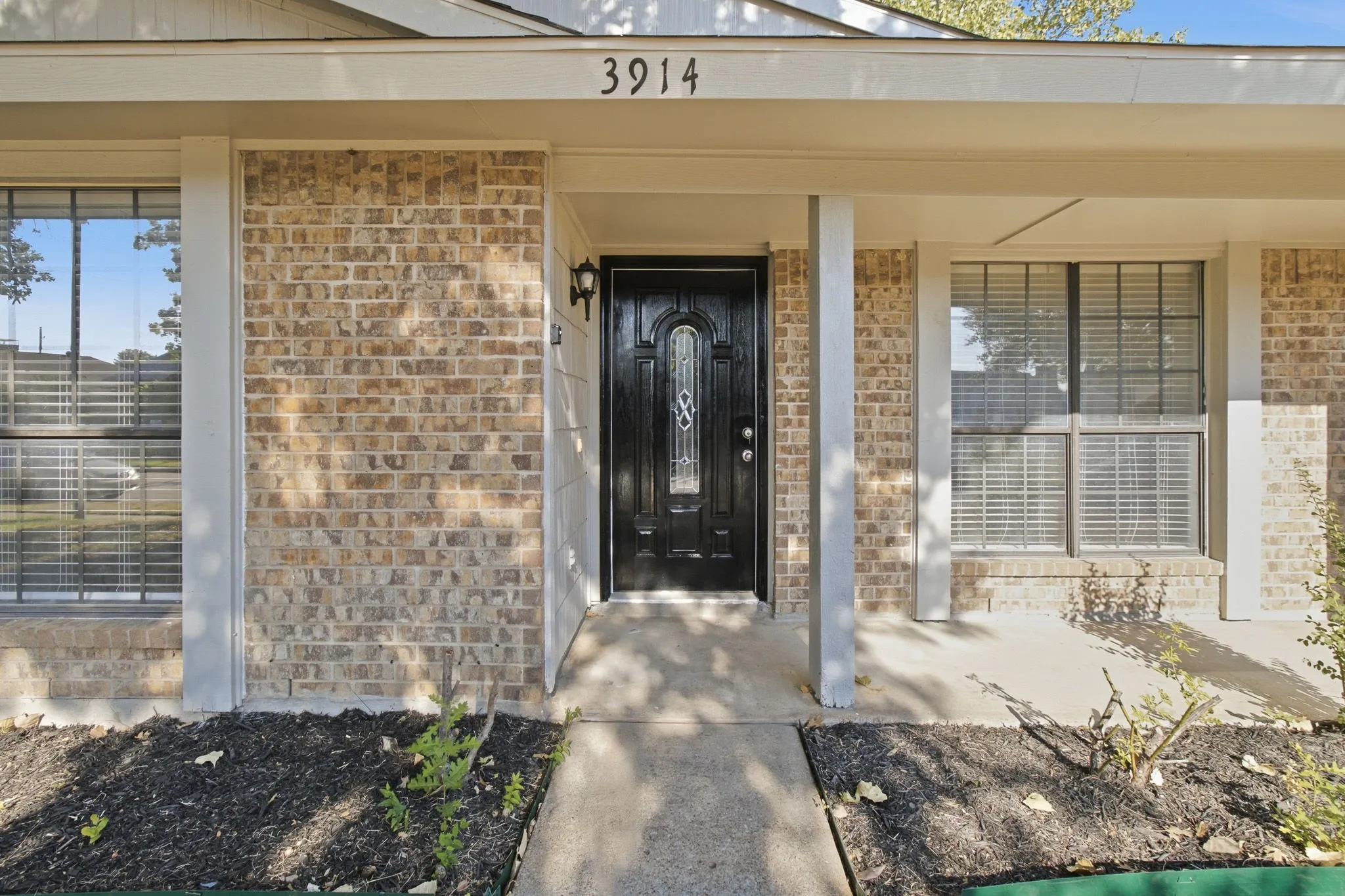 Brick exterior with a covered entry, decorative front door, and integrated house numbers