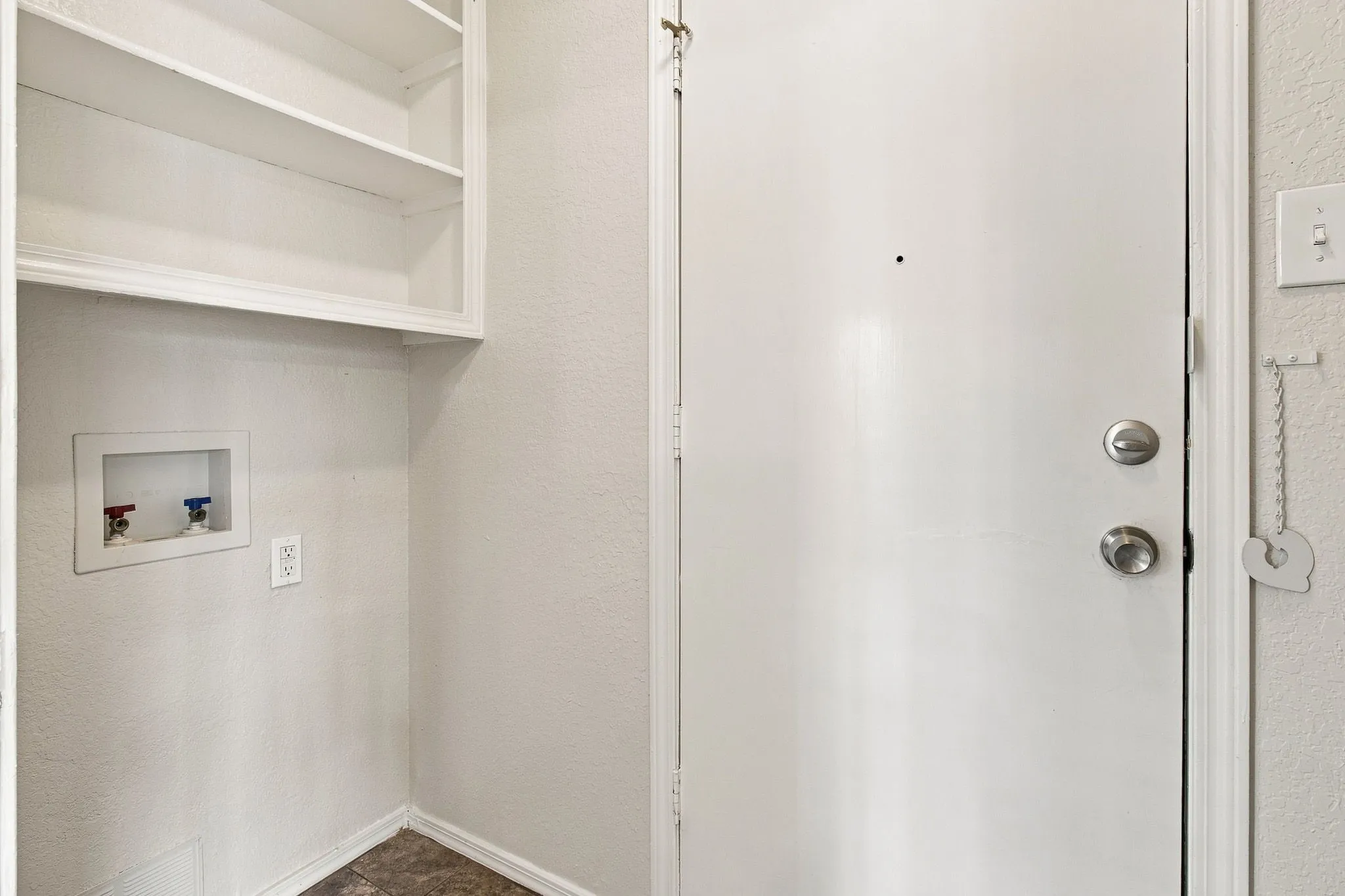 Built-in shelving, appliance hookups, and a white door with brushed metal hardware