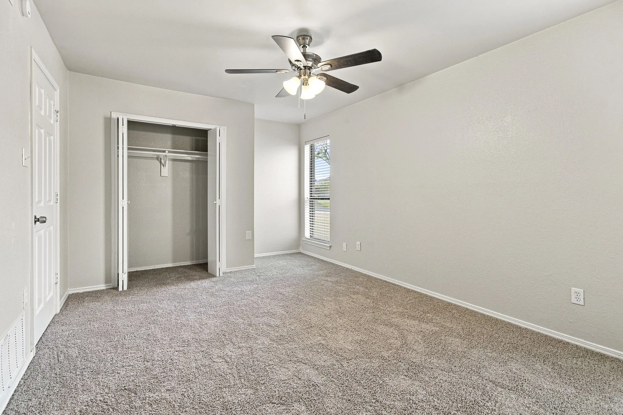 Neutral wall finishes, textured carpet, ceiling fan, bi-fold closet, and window with blinds