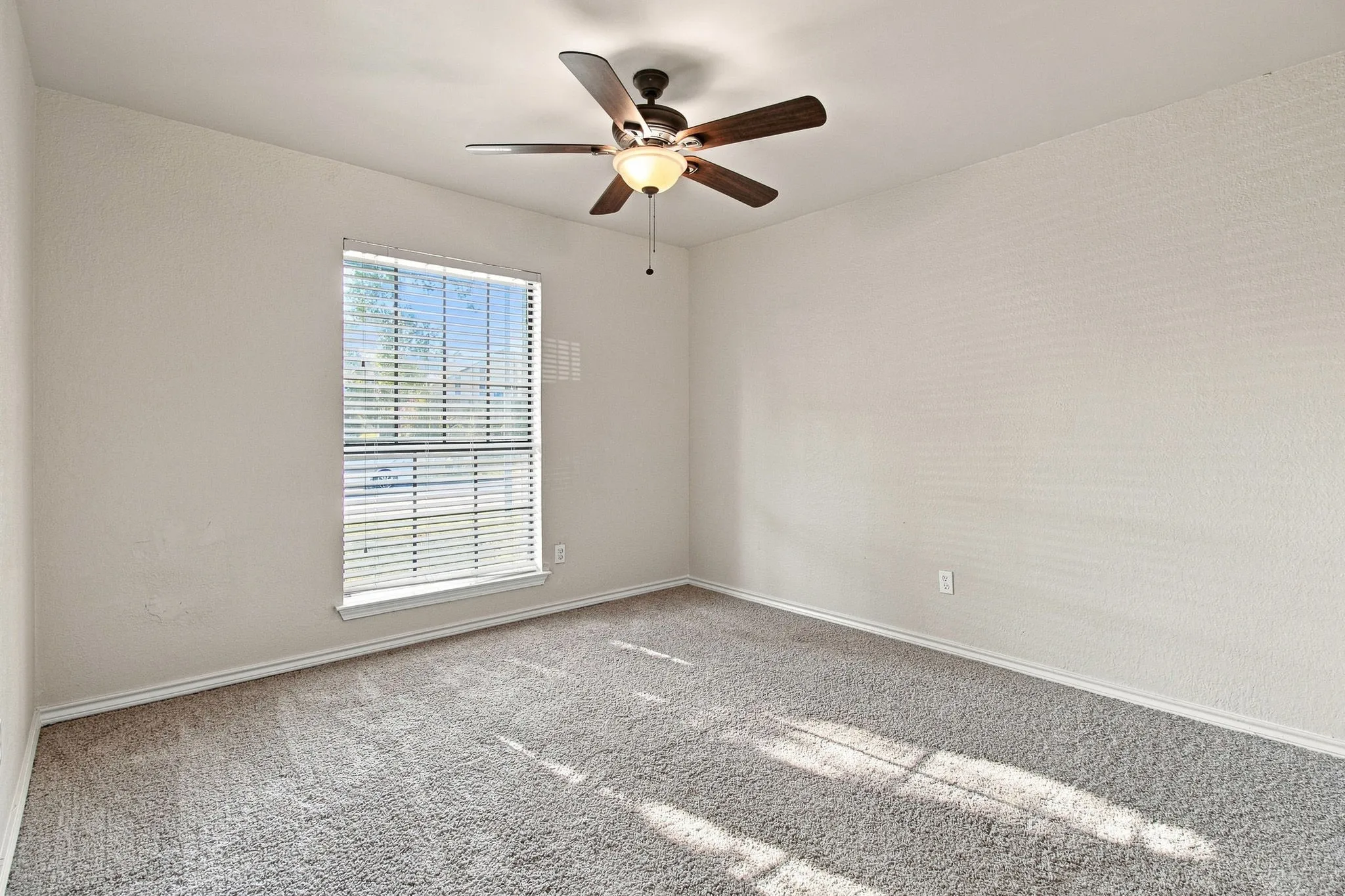 Recessed window with blinds, overhead ceiling fan with integrated lighting, and carpeted flooring