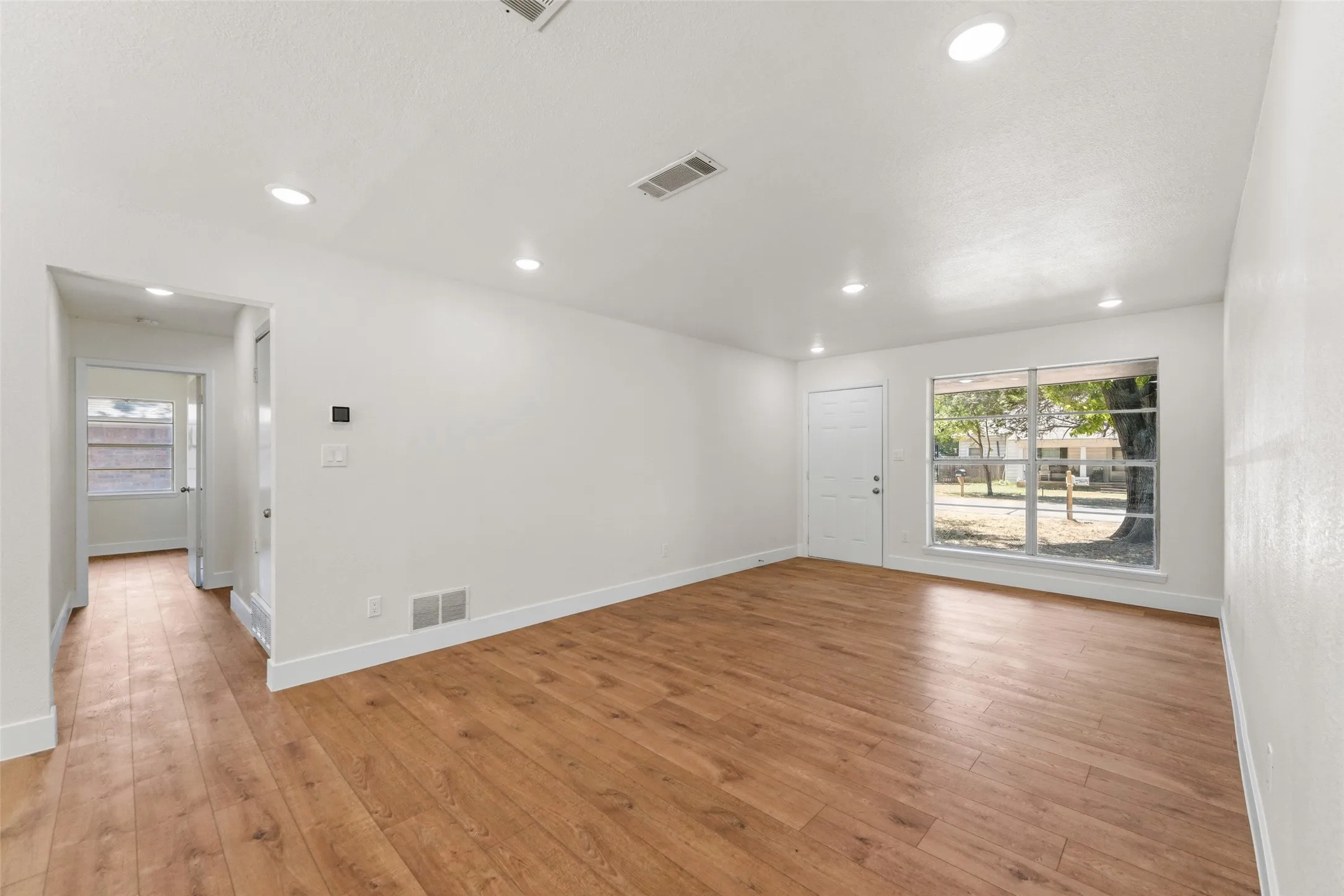 Wood-finish flooring, recessed lighting, and a front entry door with a large window