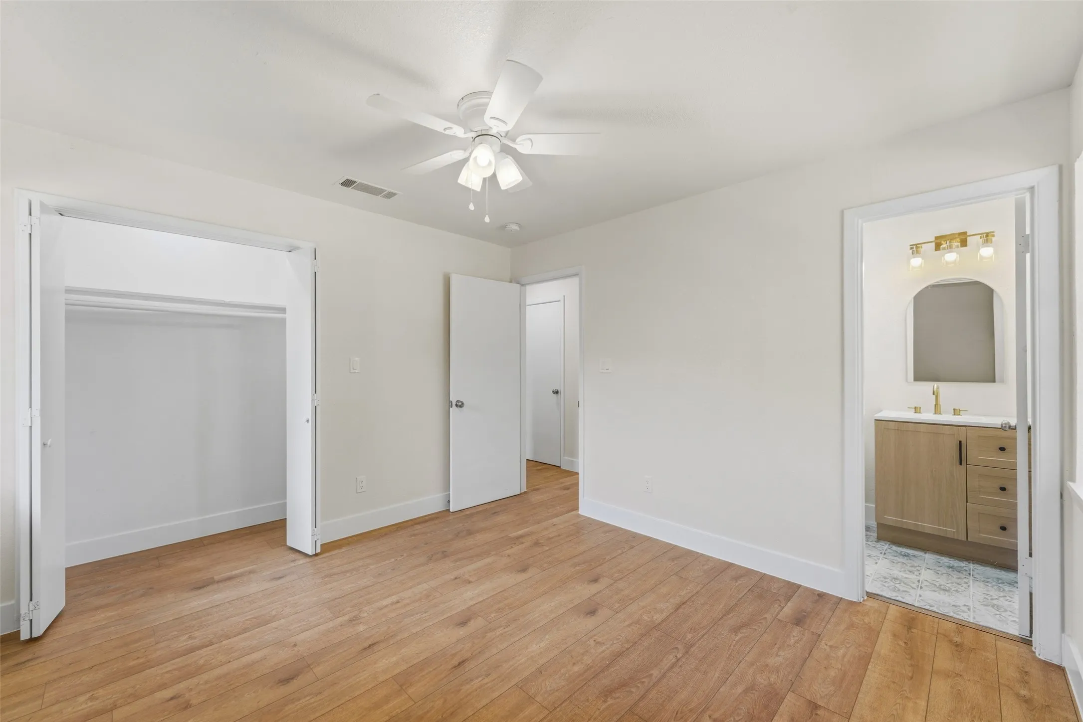 Wood-finish flooring, ceiling fan, and white walls
