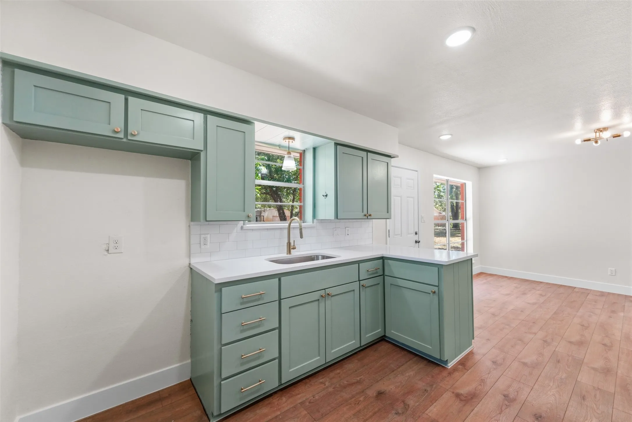 Kitchen featuring shaker-style cabinetry, white countertops, subway tile backsplash, and a stainless steel sink with a gooseneck faucet