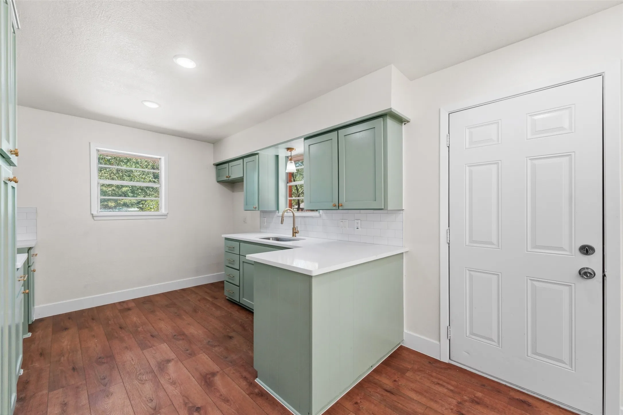 Kitchen featuring wood-finish flooring, recessed lighting, white perimeter walls, and a paneled entry door