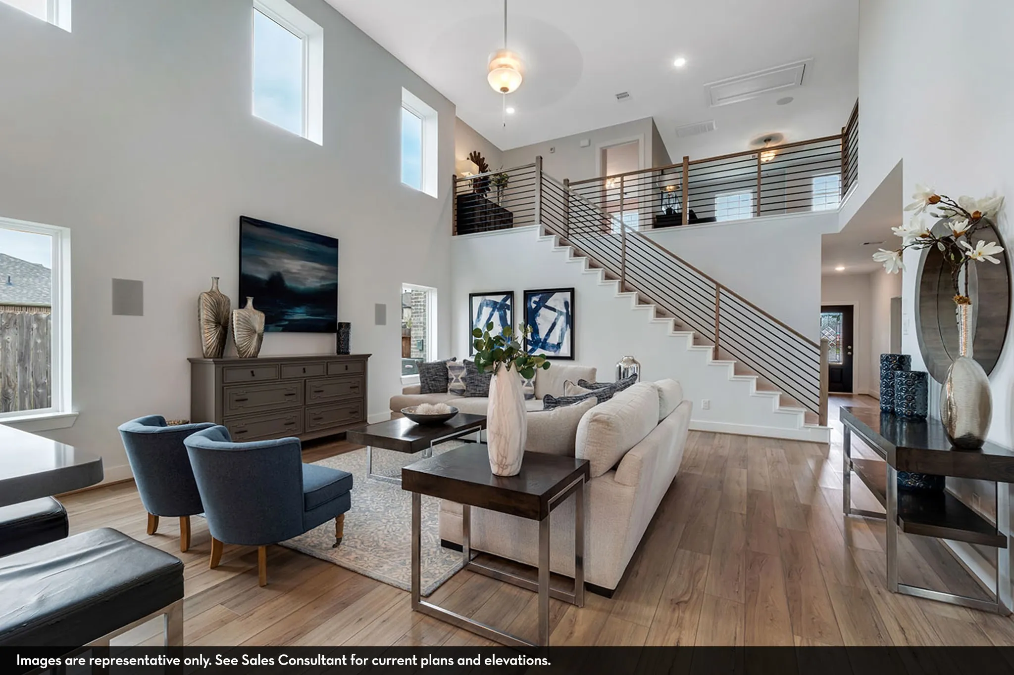 Double-height ceiling, wood-finish flooring, staircase with horizontal metal balusters, upper-level landing with horizontal metal balusters, recessed lighting