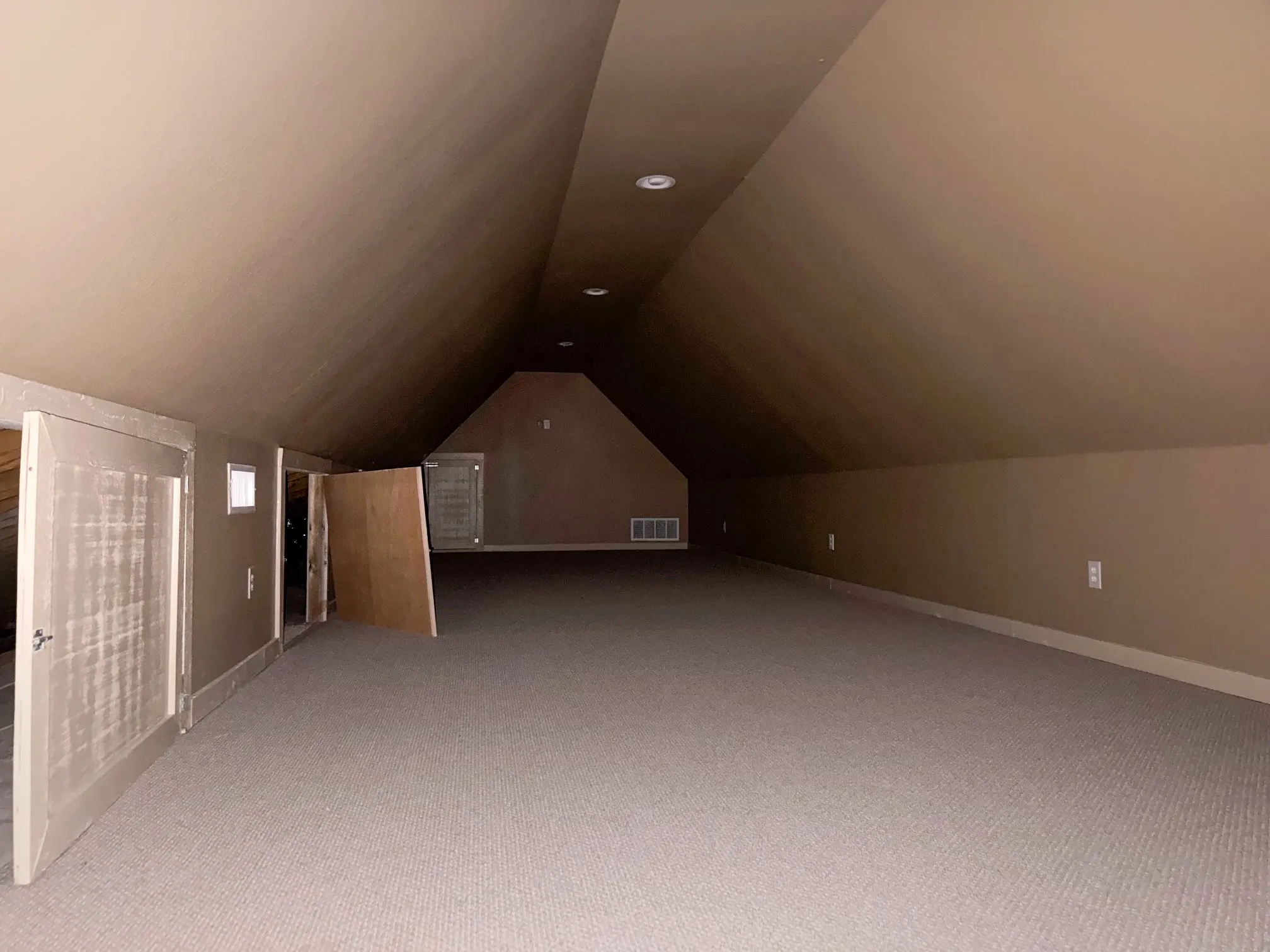Expansive carpeted area with sloped ceilings and recessed lighting