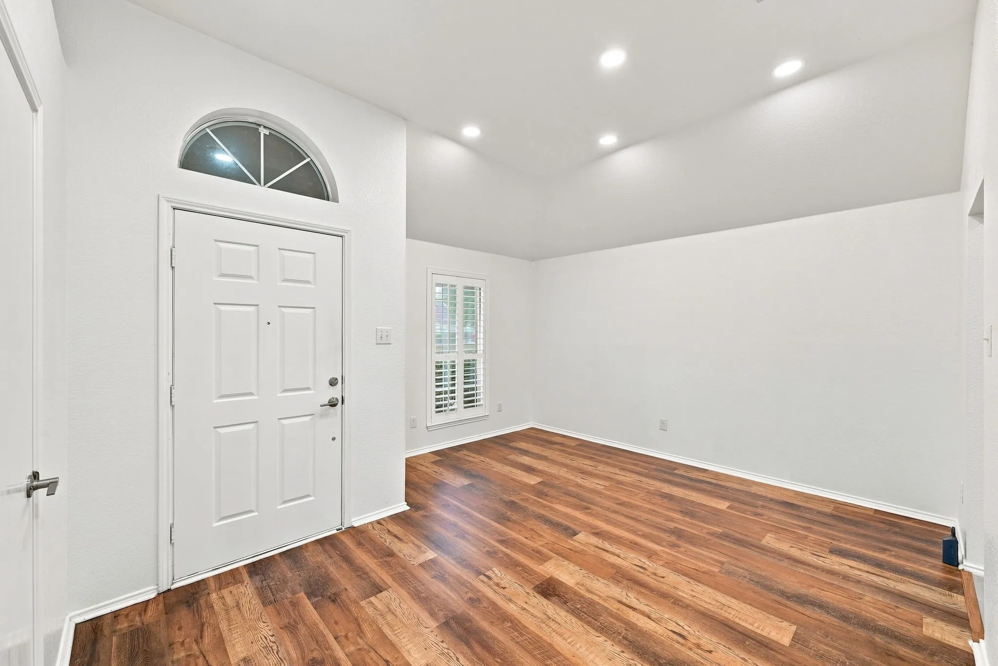 Vaulted ceilings with recessed lighting, wood-finish flooring, and white plantation shutters