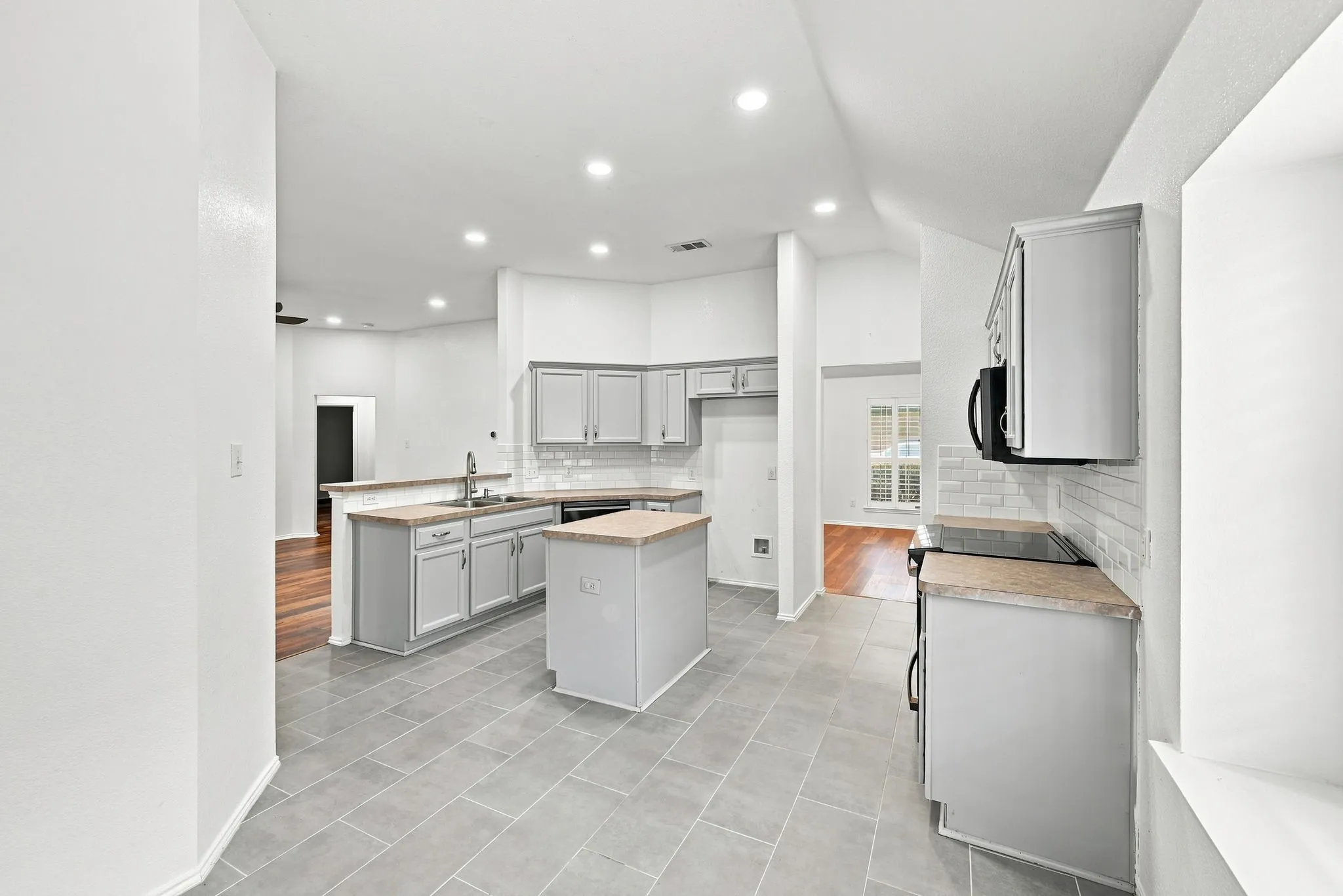 Kitchen featuring gray cabinetry, light-colored countertops, a tile backsplash, and recessed lighting