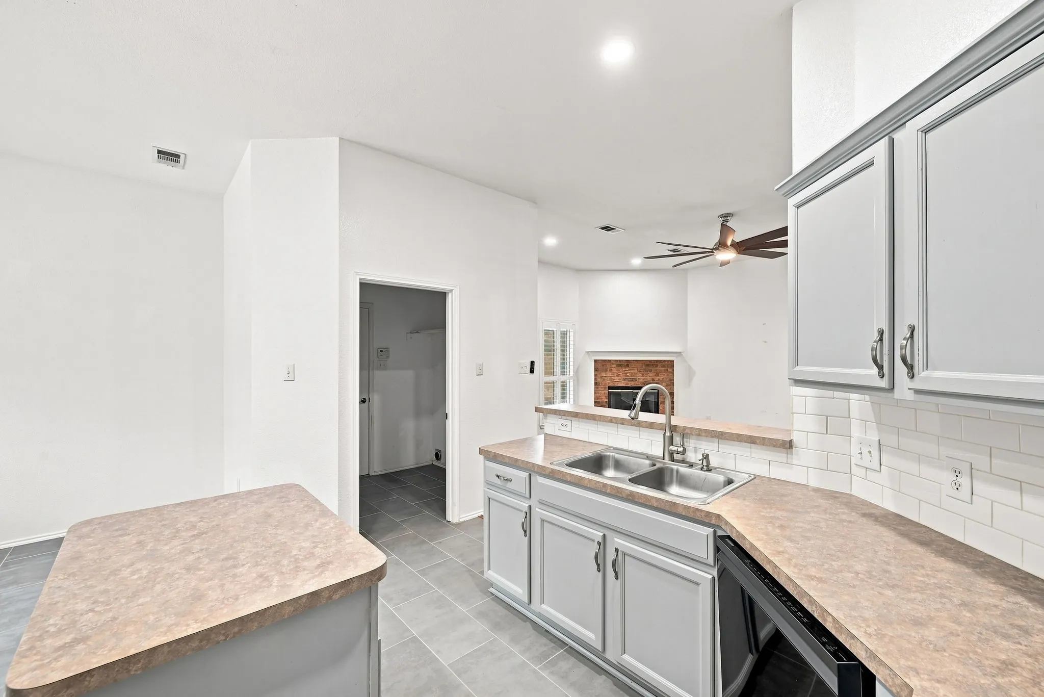 White subway tile backsplash, dual basin stainless steel sink, light gray cabinetry, and tile flooring