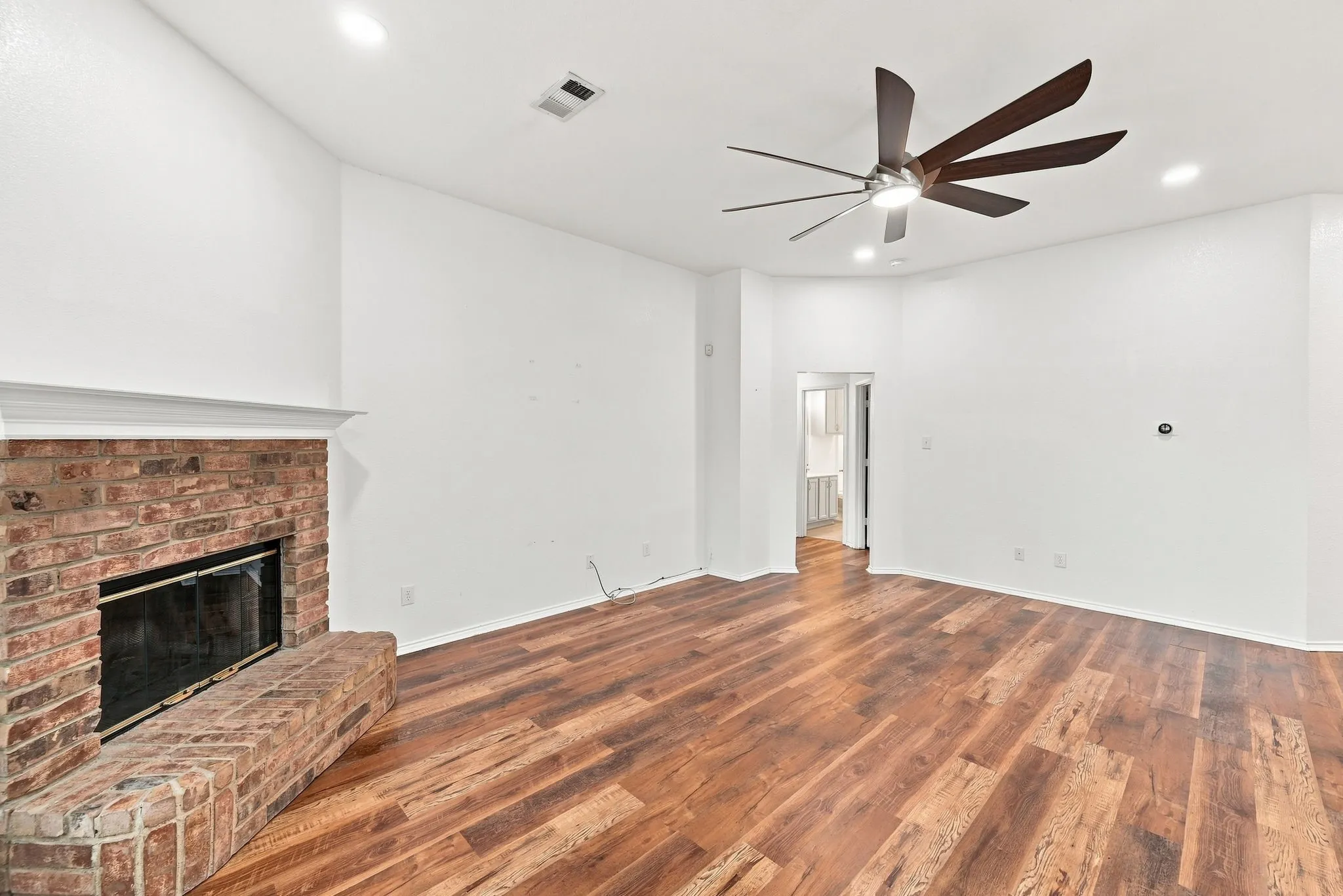 Brick fireplace with a white mantel, wood-finish flooring, recessed lighting, and a ceiling fan