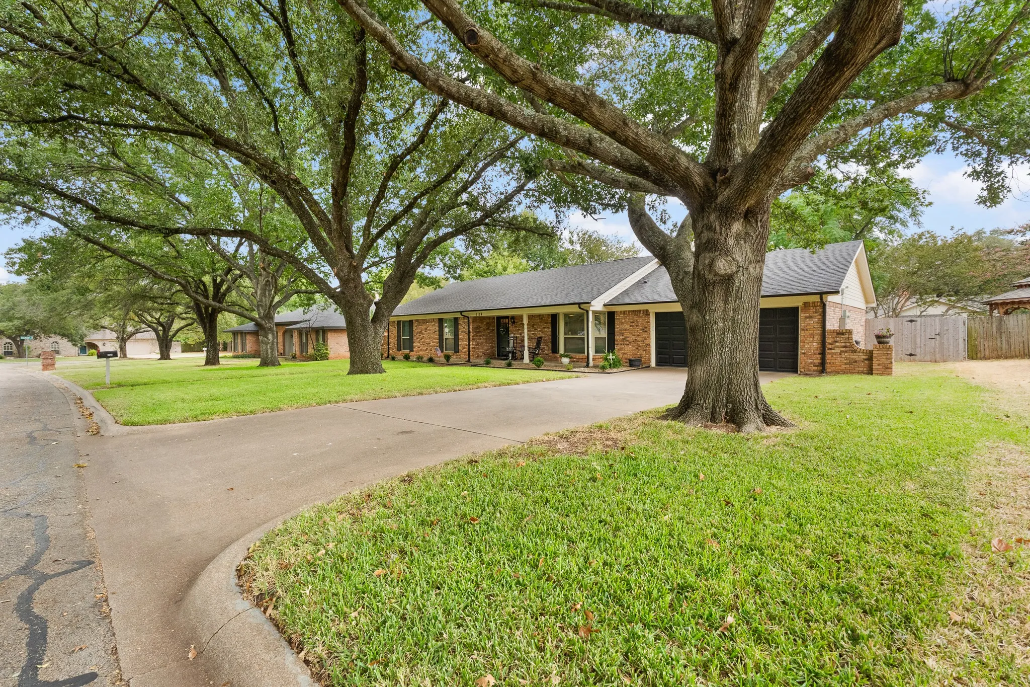 Brick exterior with a dark shingle roof, two-car garage, and an extended concrete driveway