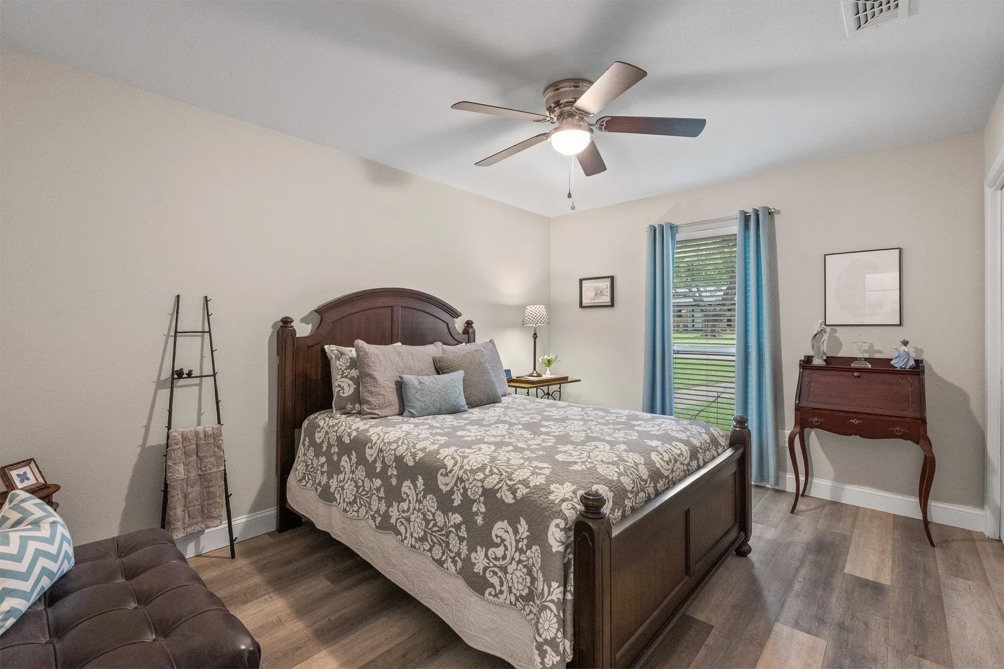 Wood-finish flooring with a neutral wall color, a ceiling fan with integrated lighting, and window blinds