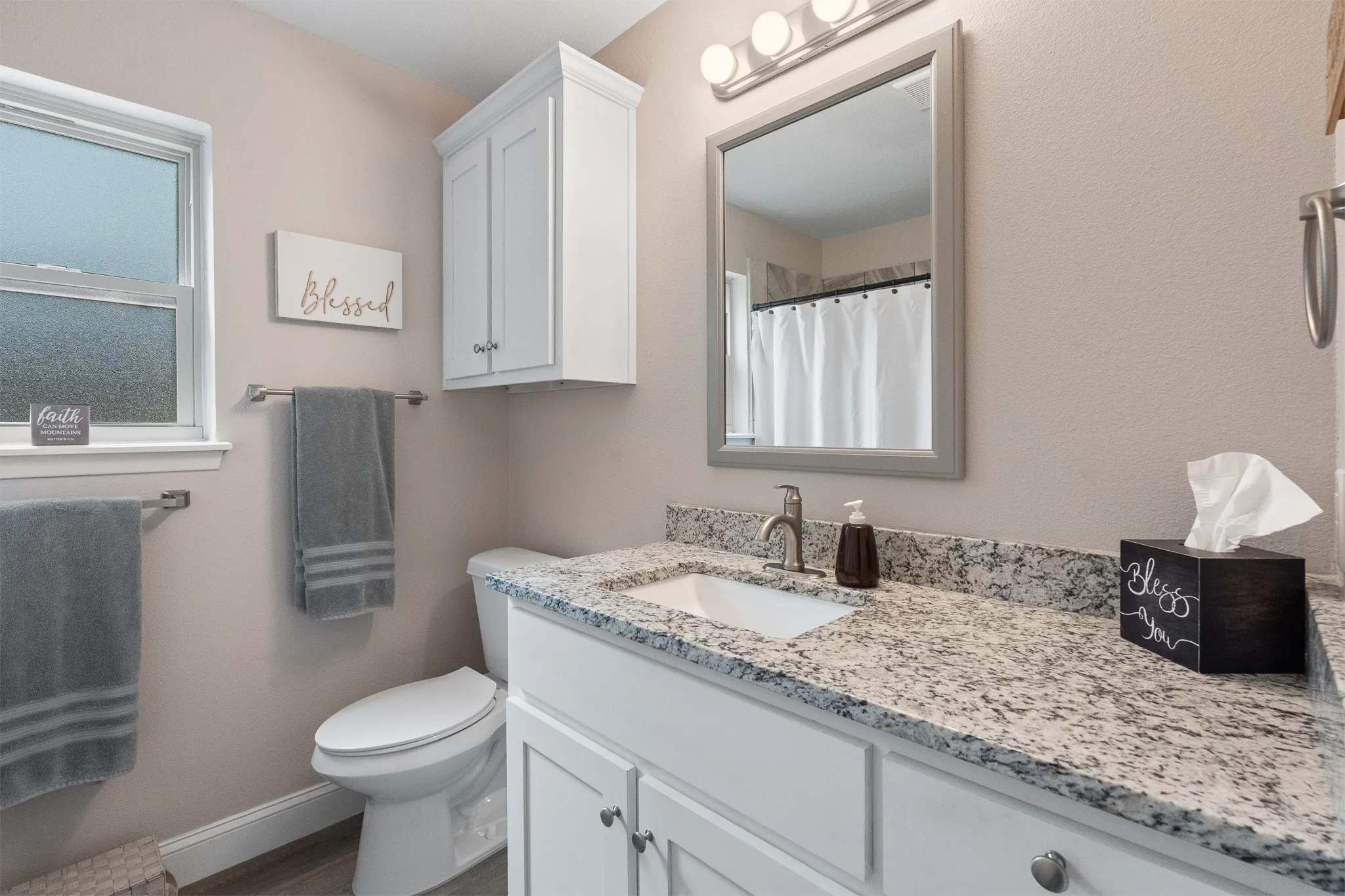 White vanity with a granite countertop and an undermount sink