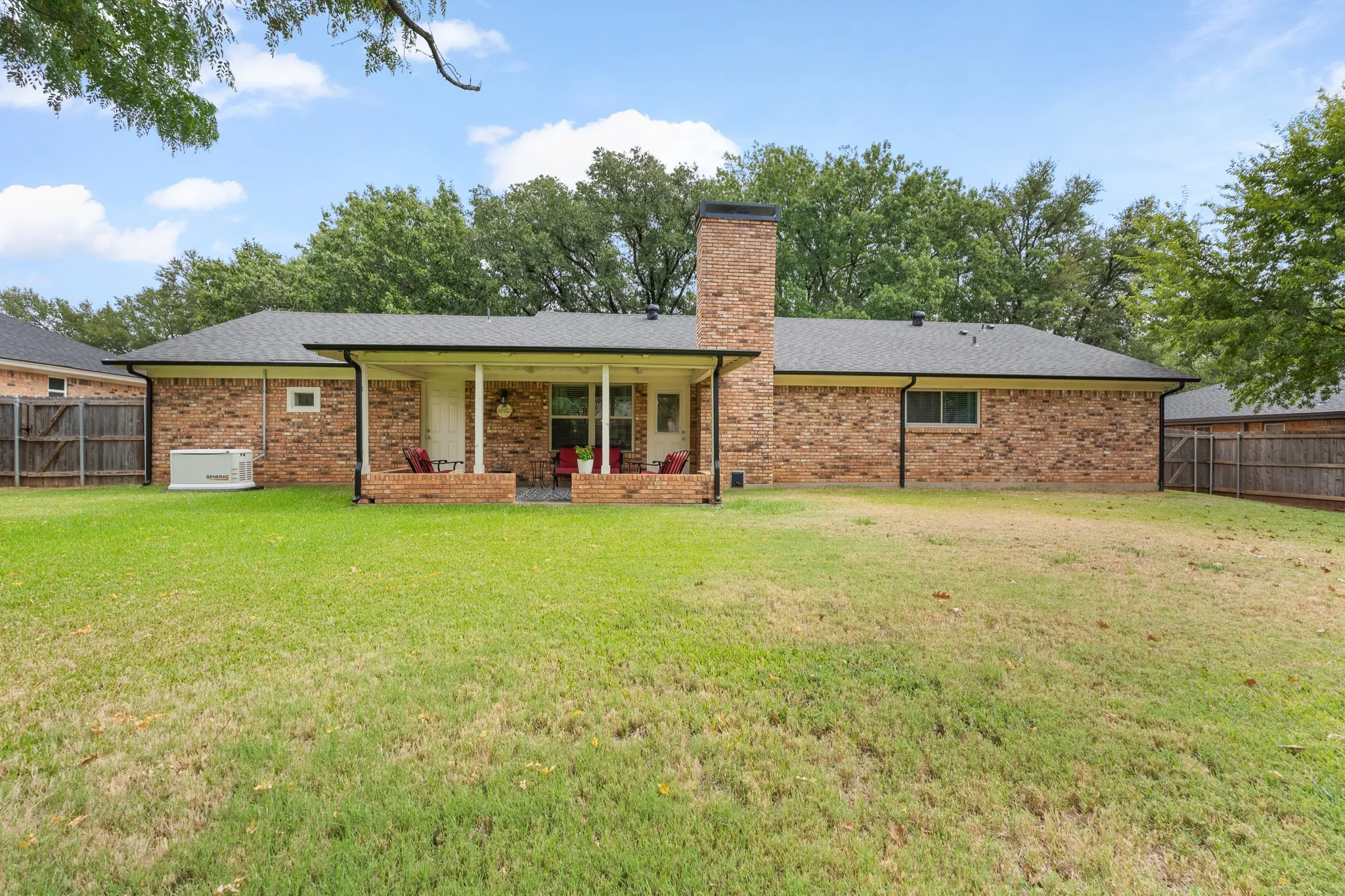 Expansive backyard featuring a covered patio, brick exterior, and established perimeter fencing