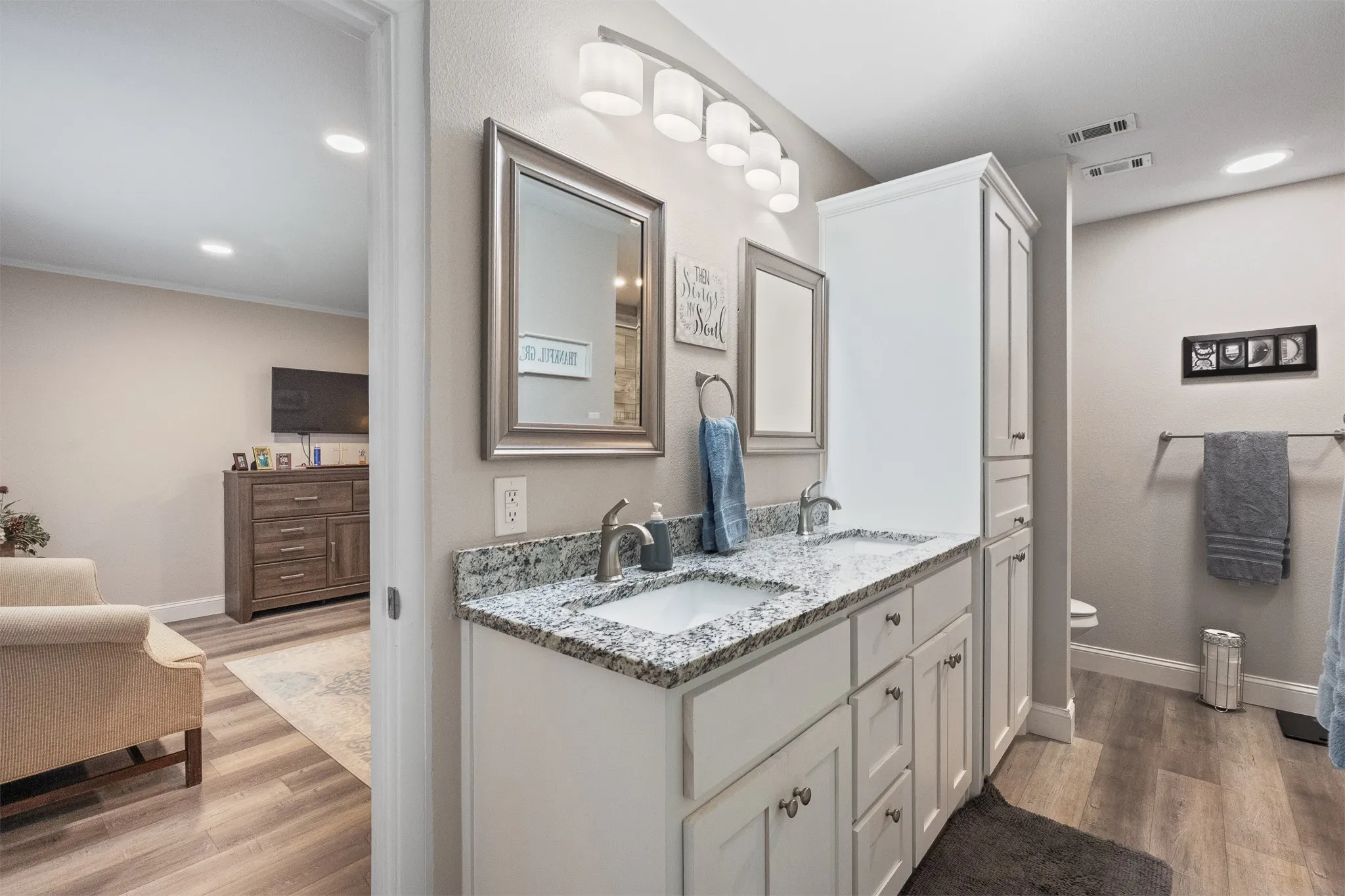Dual vanity with granite-style countertop, undermount sinks, and white cabinetry