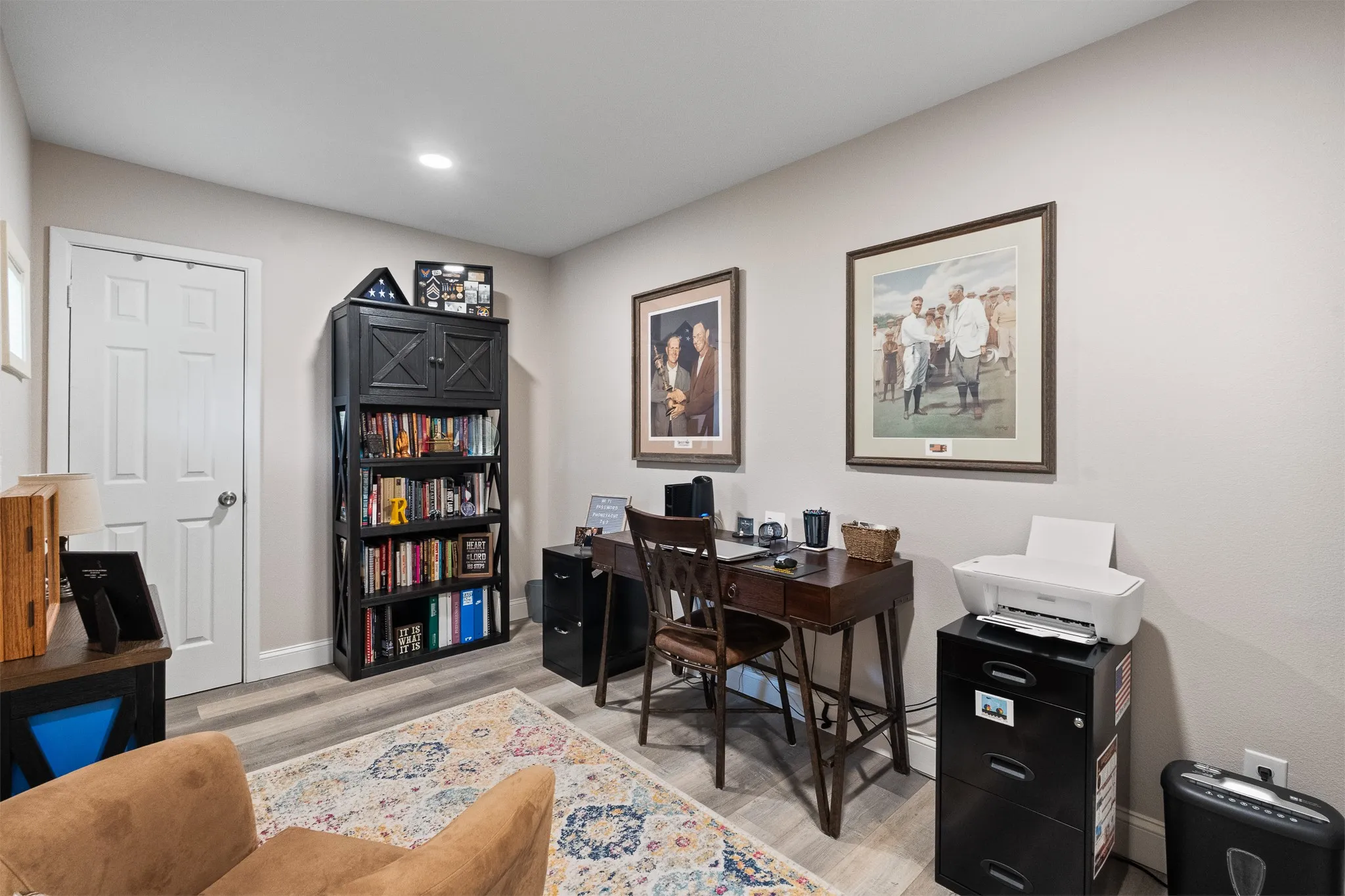 Recessed lighting, light-toned walls, a white paneled door, and wood-finish flooring
