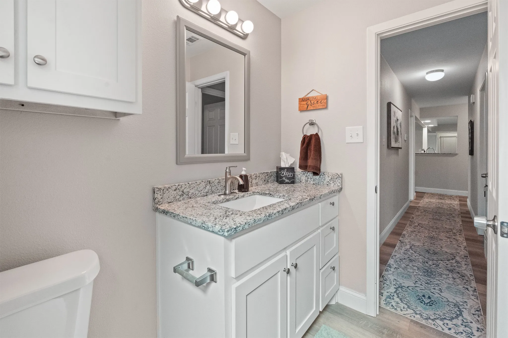 White vanity with a granite-style countertop, undermount sink, and brushed nickel faucet