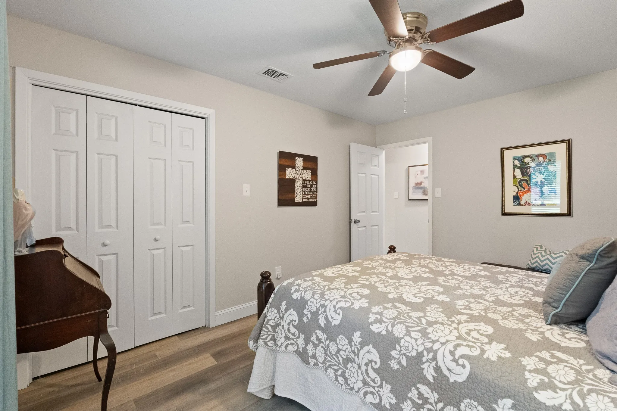 Wood-finish flooring, bi-fold closet doors, ceiling fan with integrated lighting, and neutral wall tones