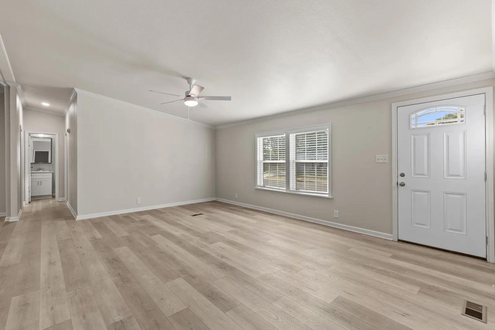 Wood-finish flooring throughout, bright white walls, and a ceiling fan with integrated lighting