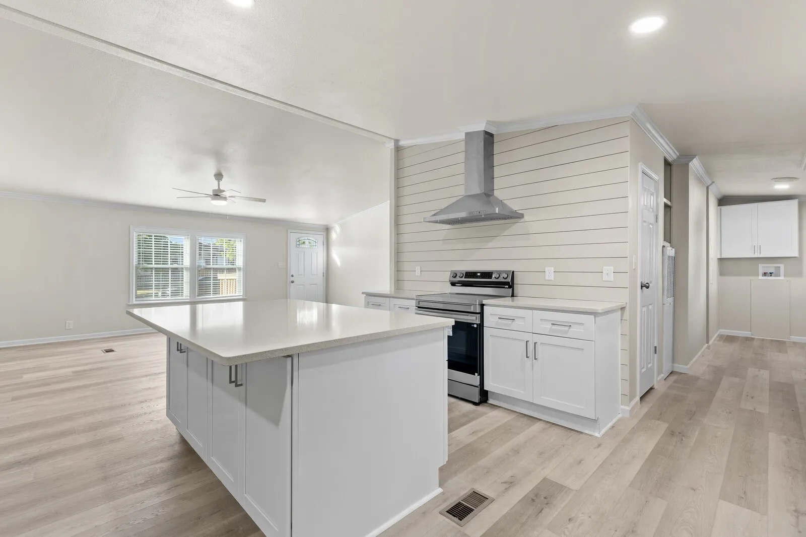 Kitchen featuring a central island with countertop, shaker-style cabinetry, wood-finish flooring, a stainless steel range with overhead hood, and recessed lighting