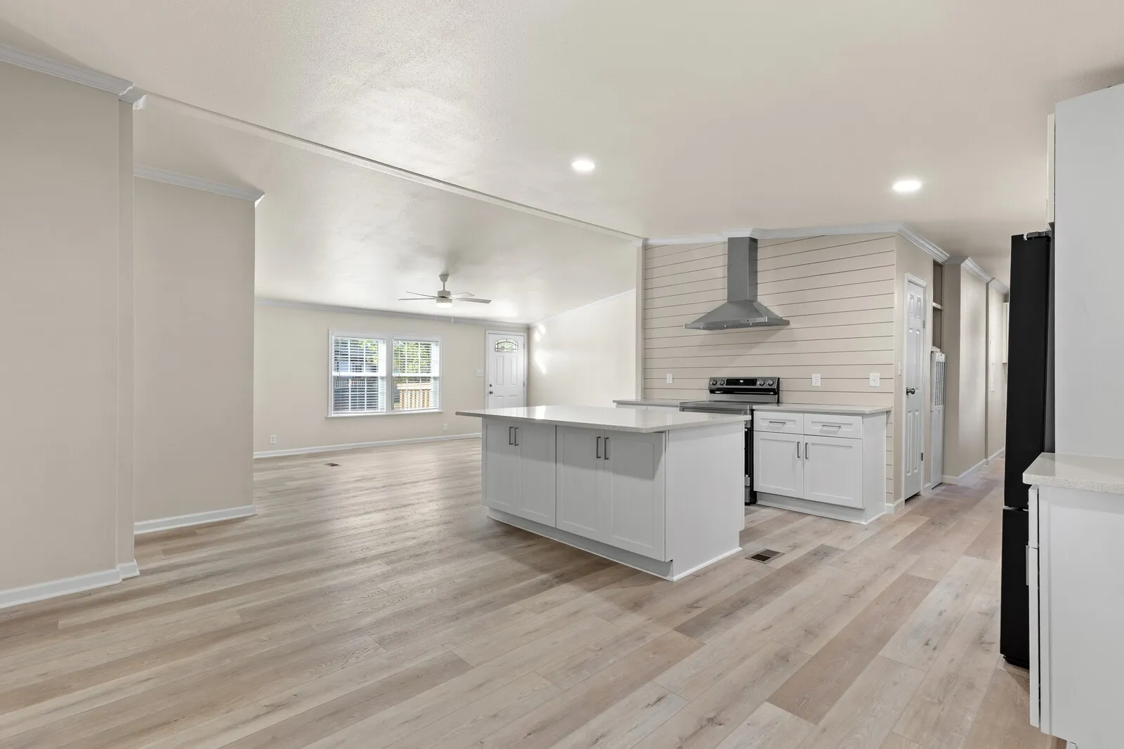 Open-concept layout featuring wood-finish flooring, recessed lighting, a kitchen island with storage, and stainless steel appliances
