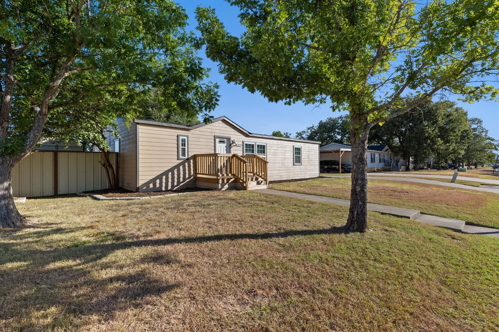 Exterior siding with contrasting trim, elevated wood-finish entry deck, and a partially fenced yard