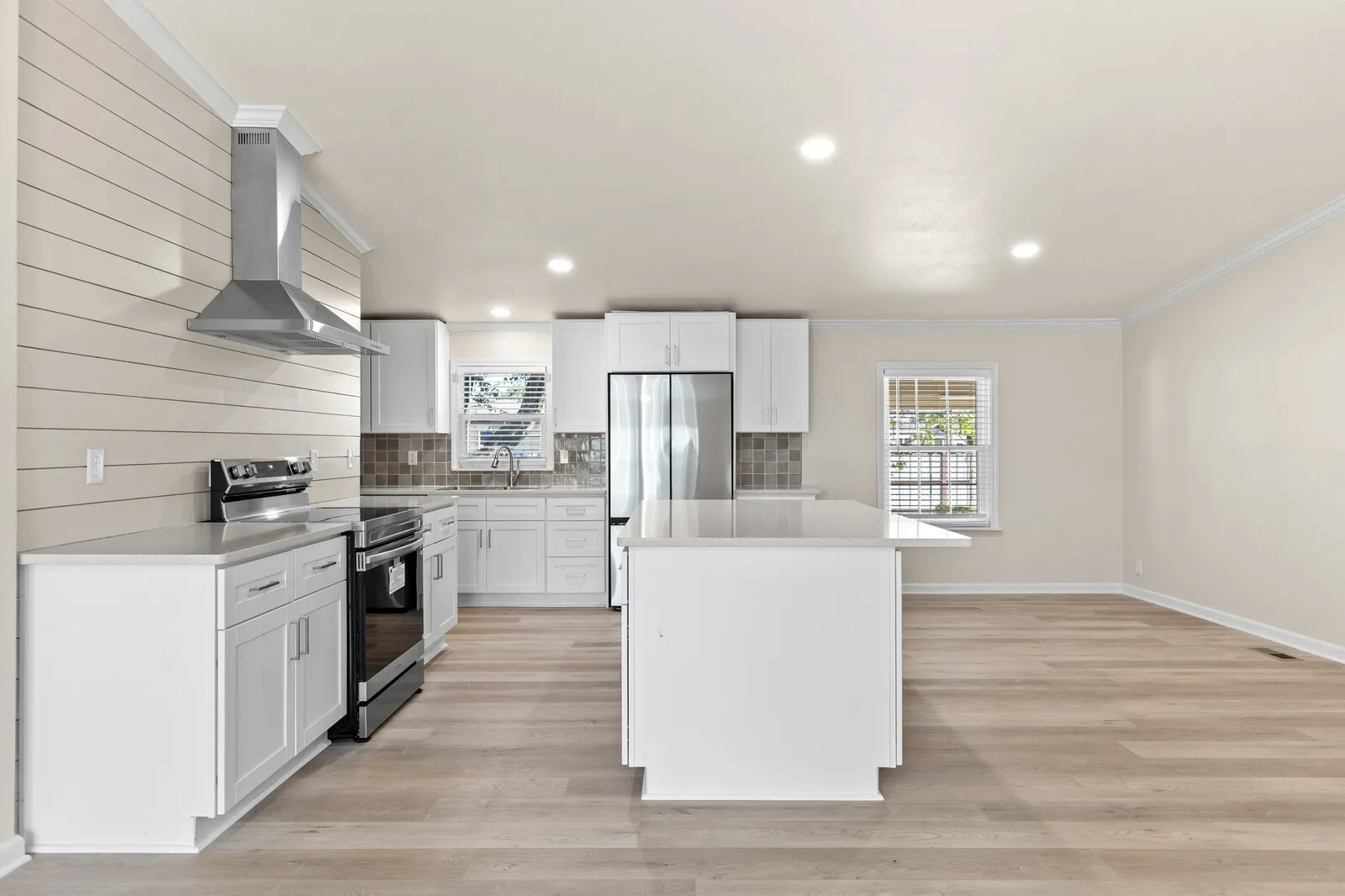 Kitchen featuring white cabinetry, stainless steel appliances, a center island with countertop seating, and wood-finish flooring