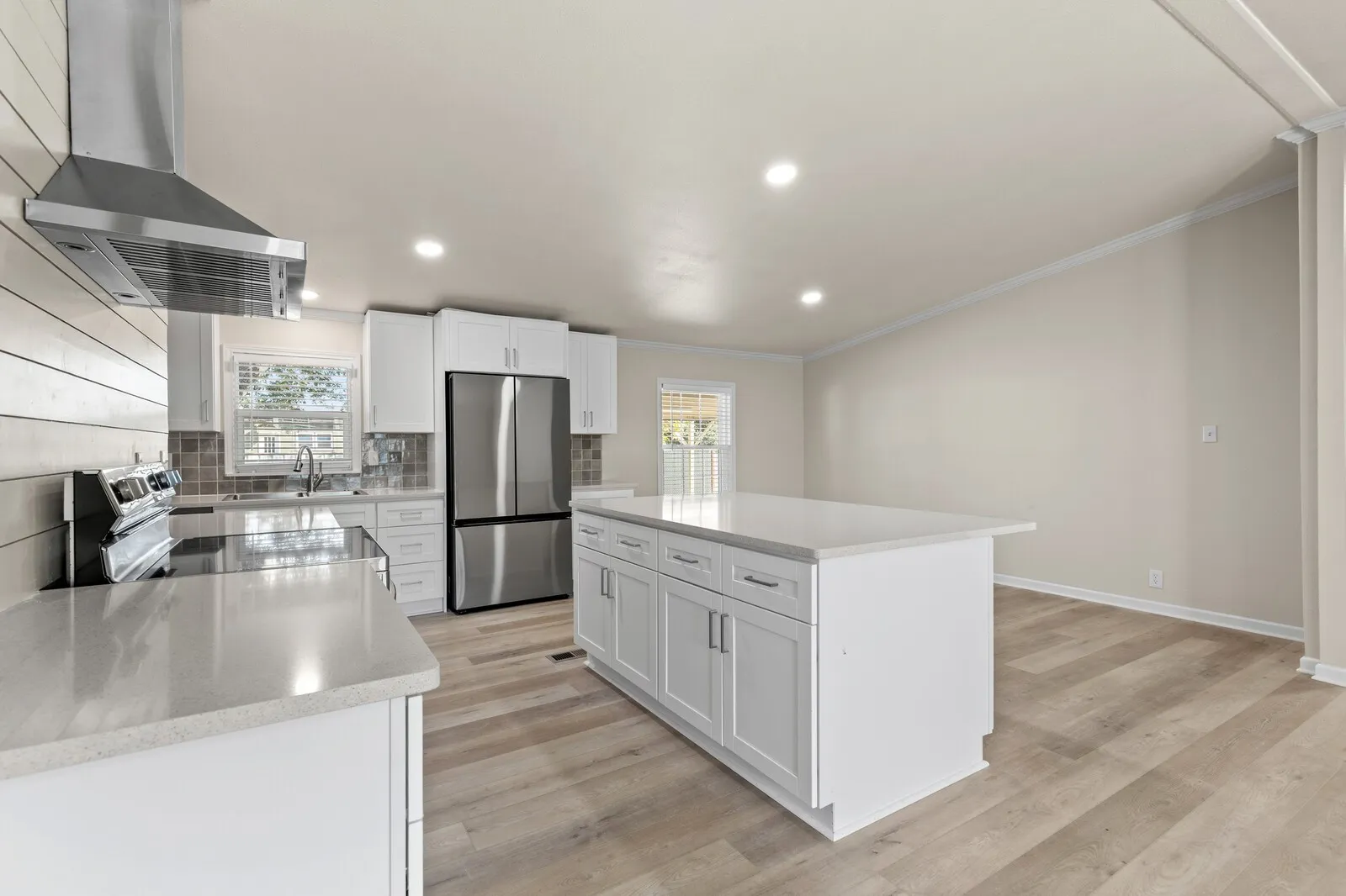 Kitchen featuring a central island, stainless steel appliances, white cabinetry, and light wood-finish flooring