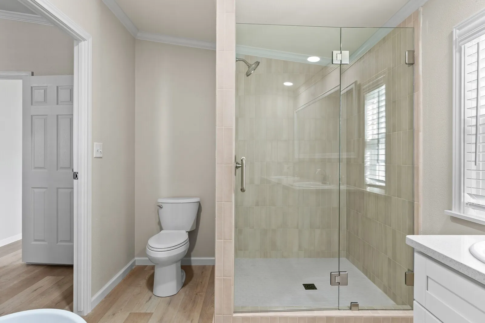 Glass-enclosed shower with tile surround, recessed lighting, and a window with blinds