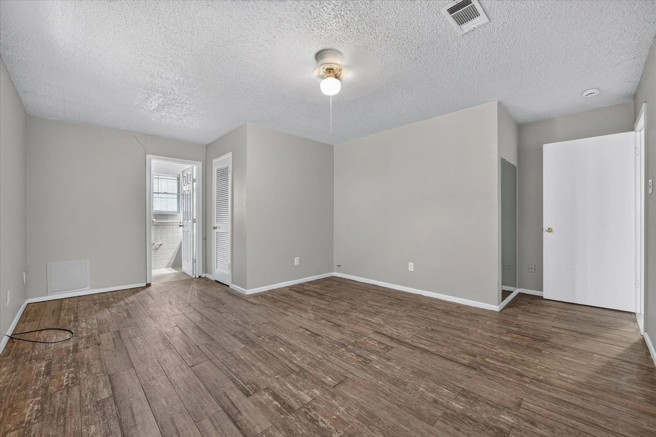 Wood-finish flooring, light grey wall paint, and a ceiling-mounted light fixture