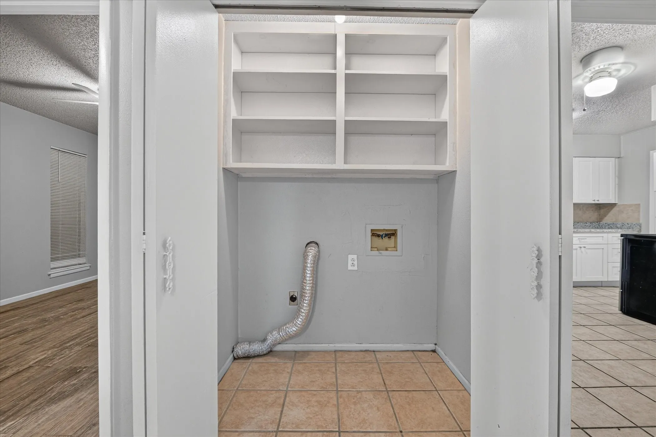 Utility closet with tiled flooring and built-in shelving