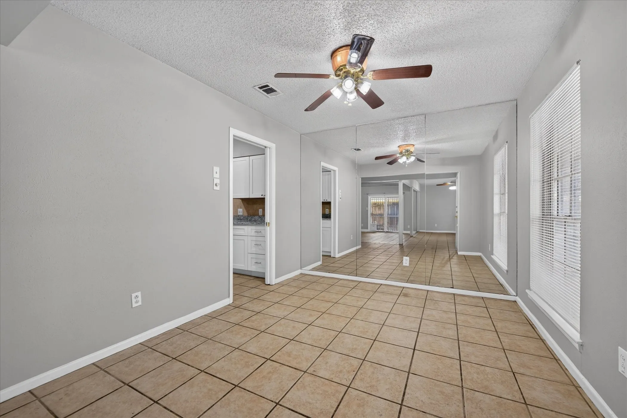 Tile flooring throughout, full wall mirrored accent, and two windows with blinds