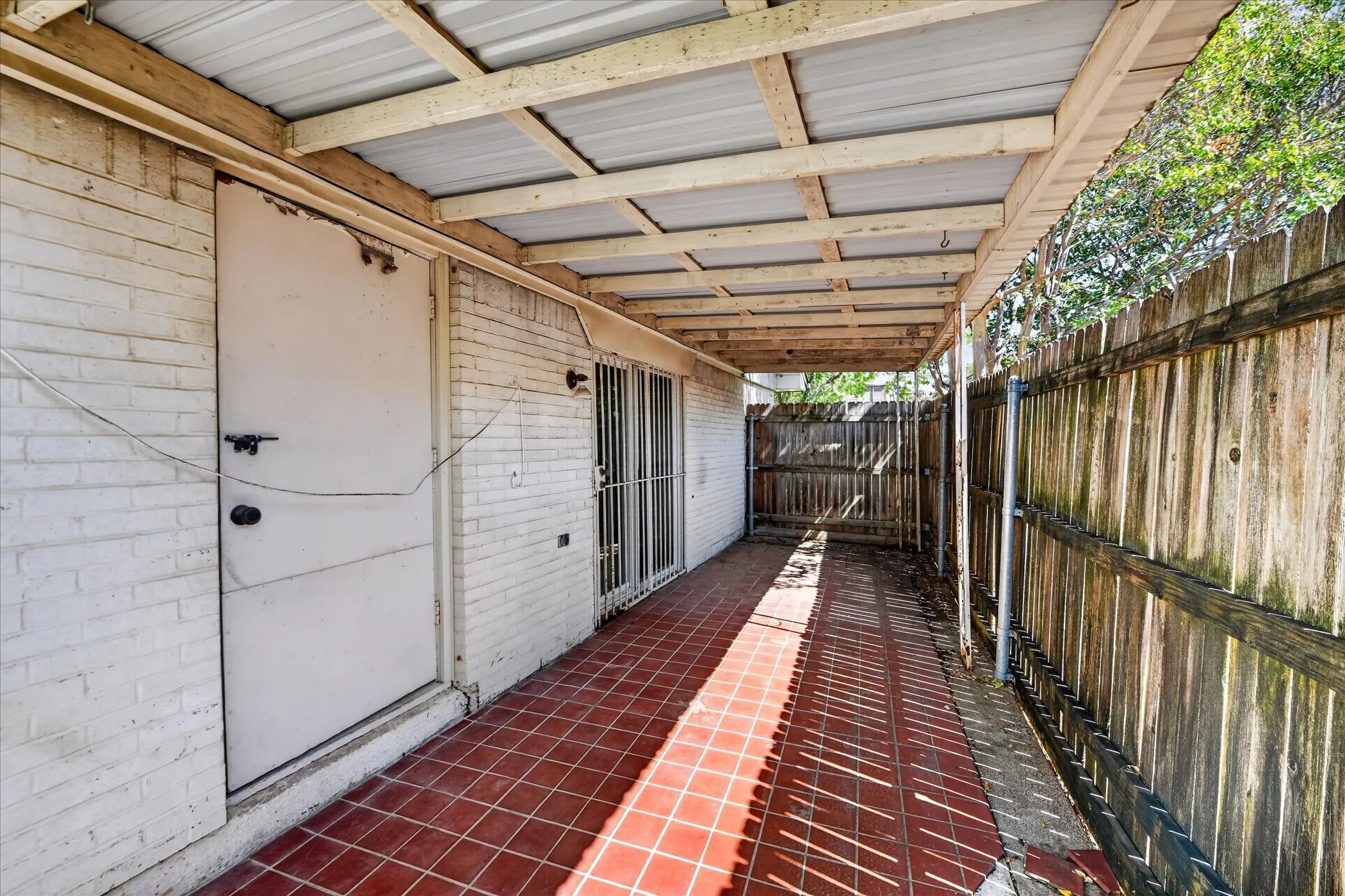 Covered patio featuring a metal roof, wood framing, and terracotta tile flooring
