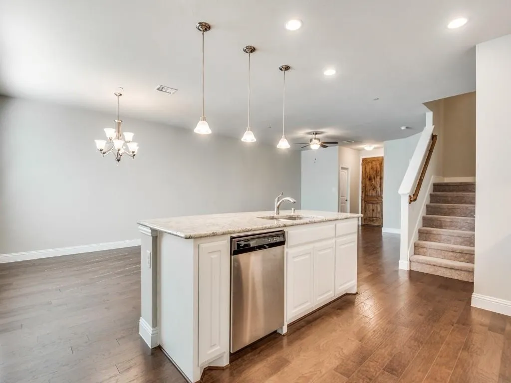 Kitchen island with built-in sink and dishwasher, wood-finish flooring, recessed lighting, and a carpeted staircase