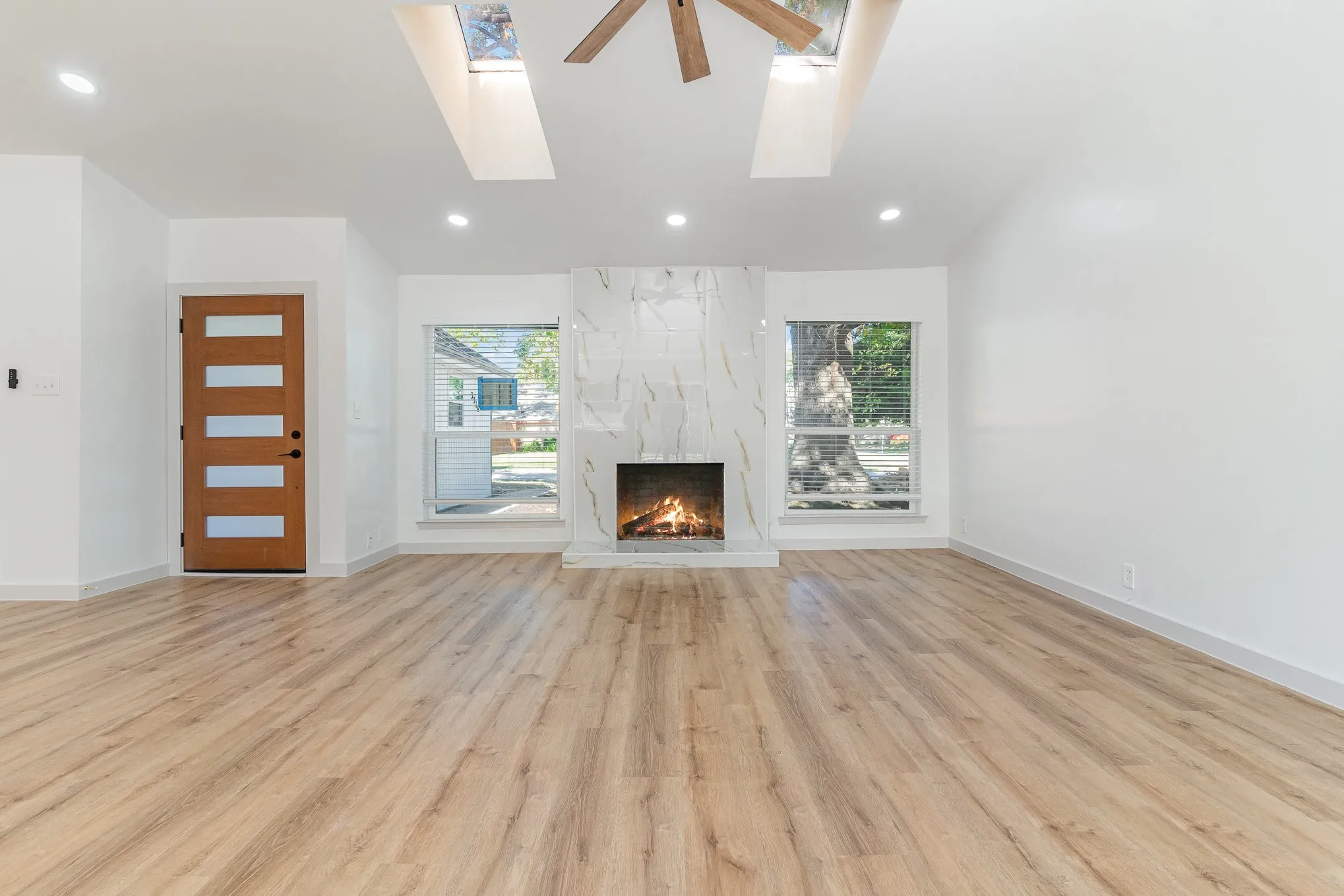 Unfurnished living room with a fireplace, light wood-type flooring, a skylight, and a wealth of natural light