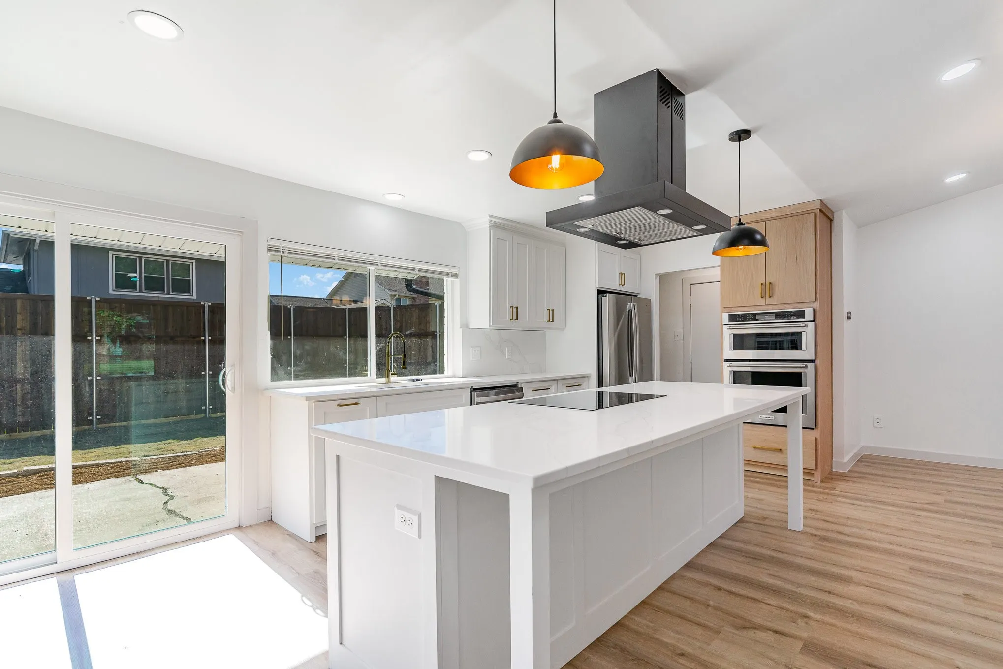 Kitchen featuring island exhaust hood, appliances with stainless steel finishes, pendant lighting, white cabinetry, and a kitchen island