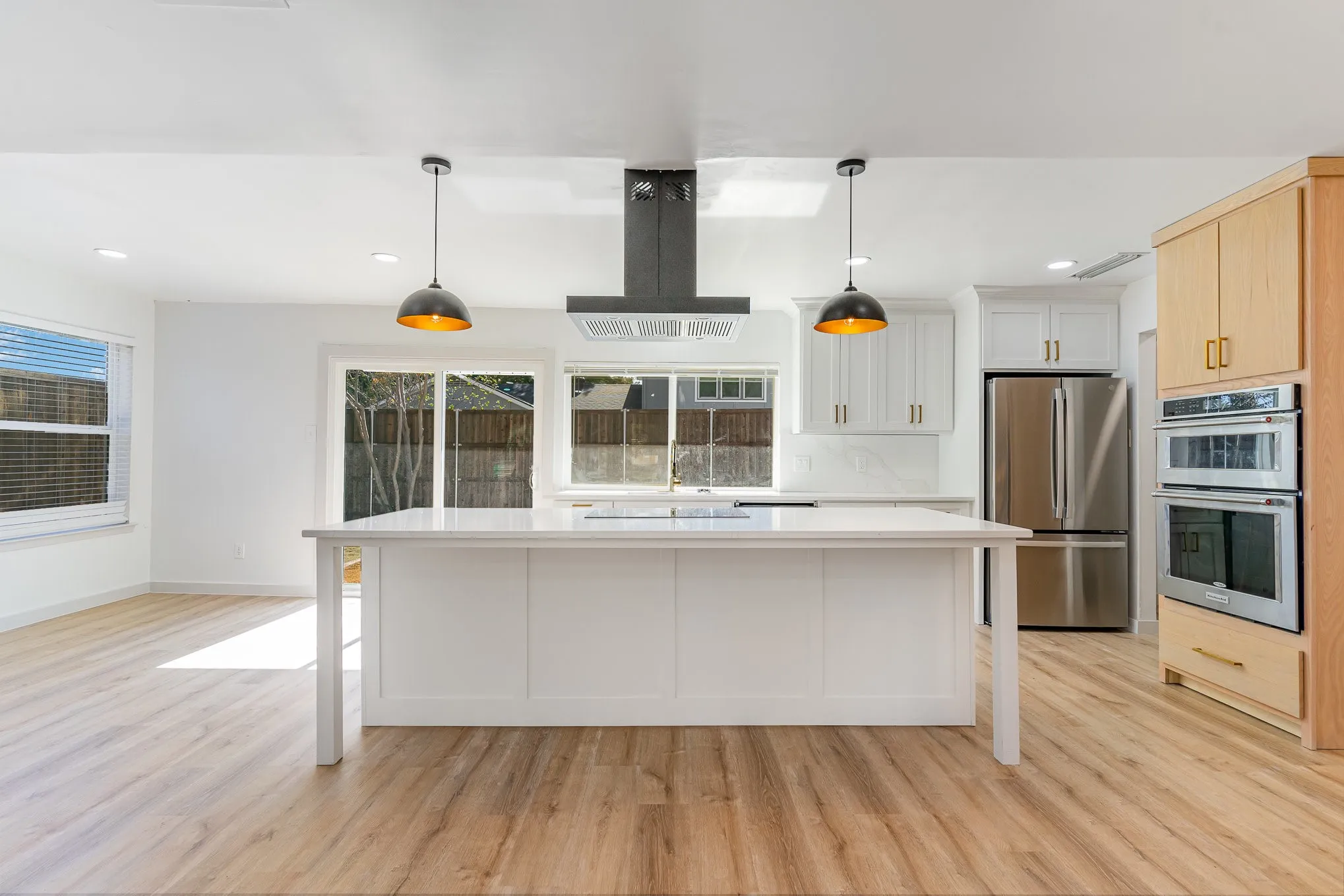 Kitchen featuring stainless steel appliances, extractor fan, hanging light fixtures, and white cabinetry