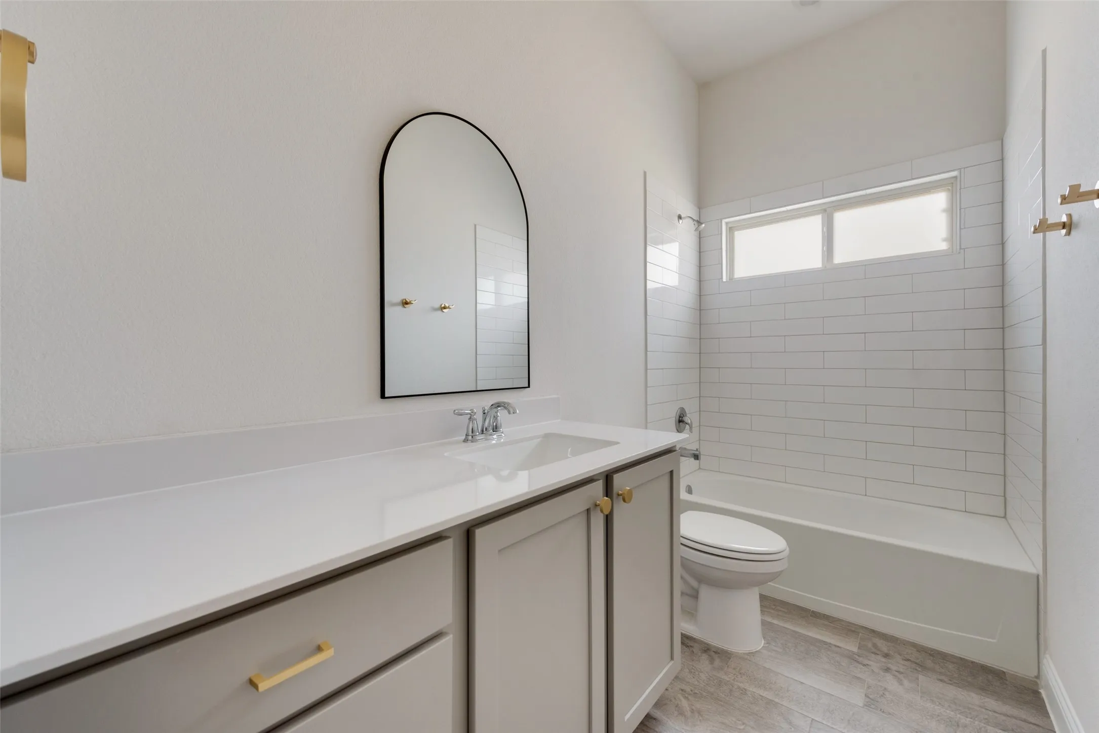 Full bathroom with tiled shower / bath, vanity, toilet, and wood-type flooring