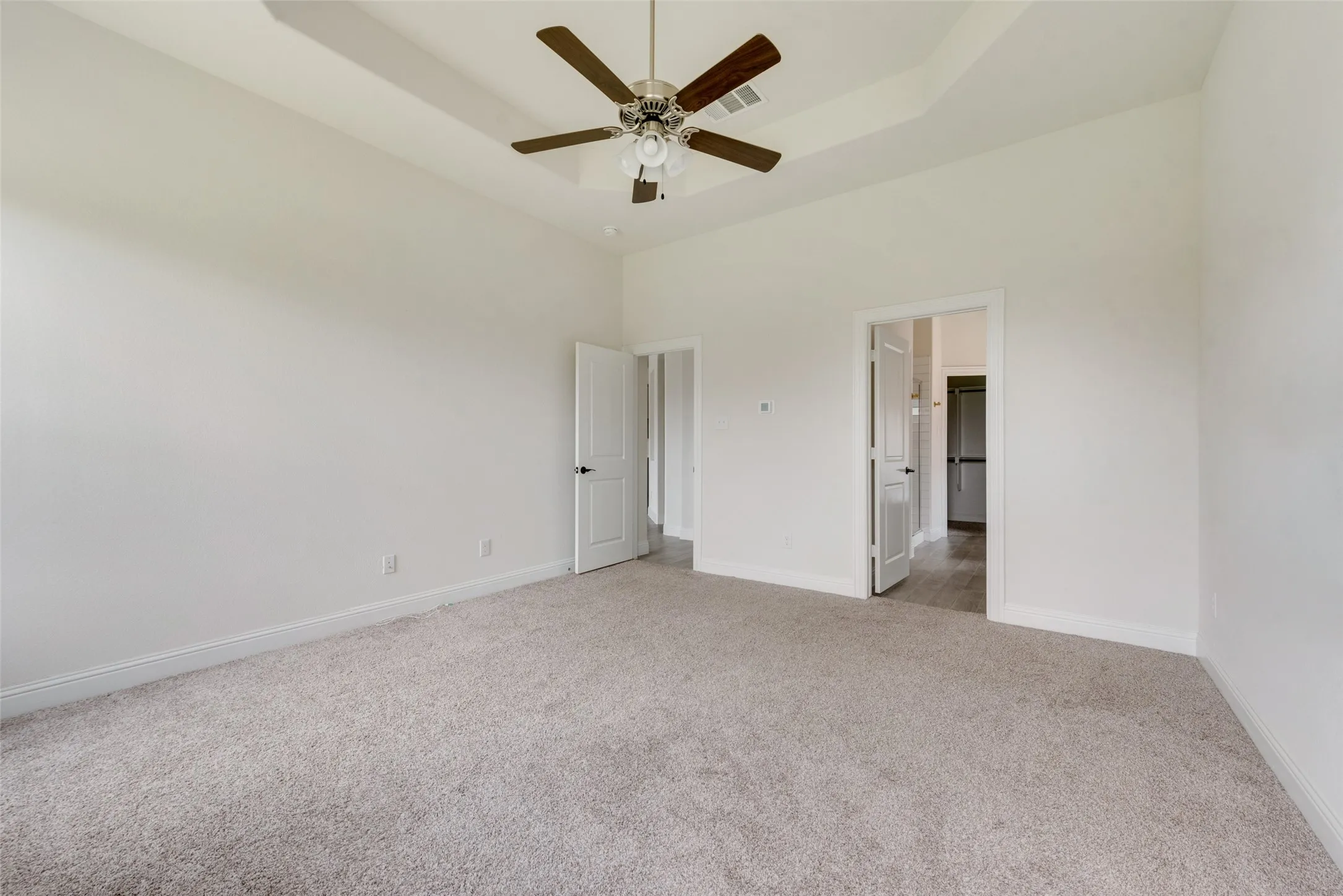Unfurnished room with a high ceiling, carpet flooring, ceiling fan, and a raised ceiling