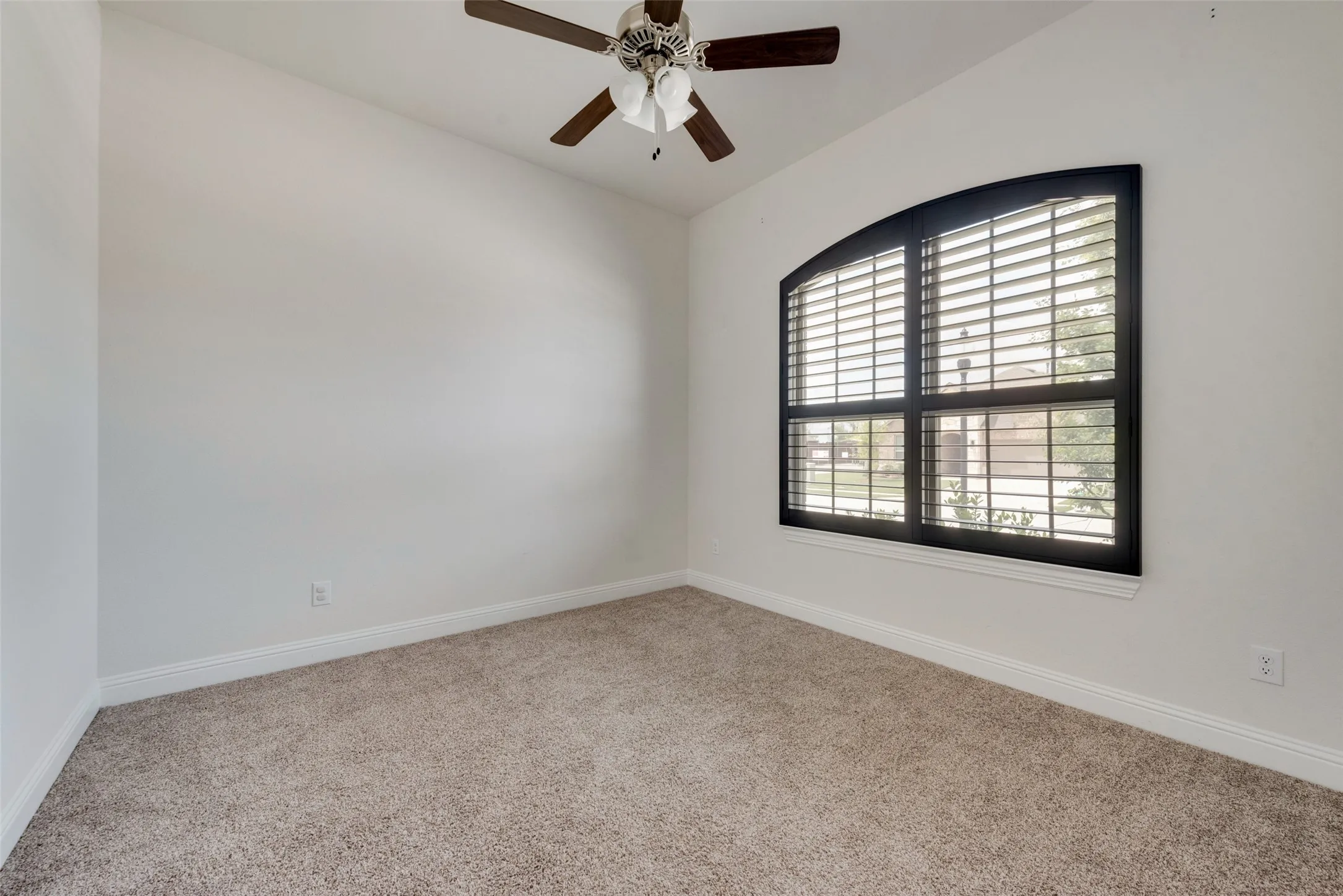 Carpeted empty room featuring ceiling fan
