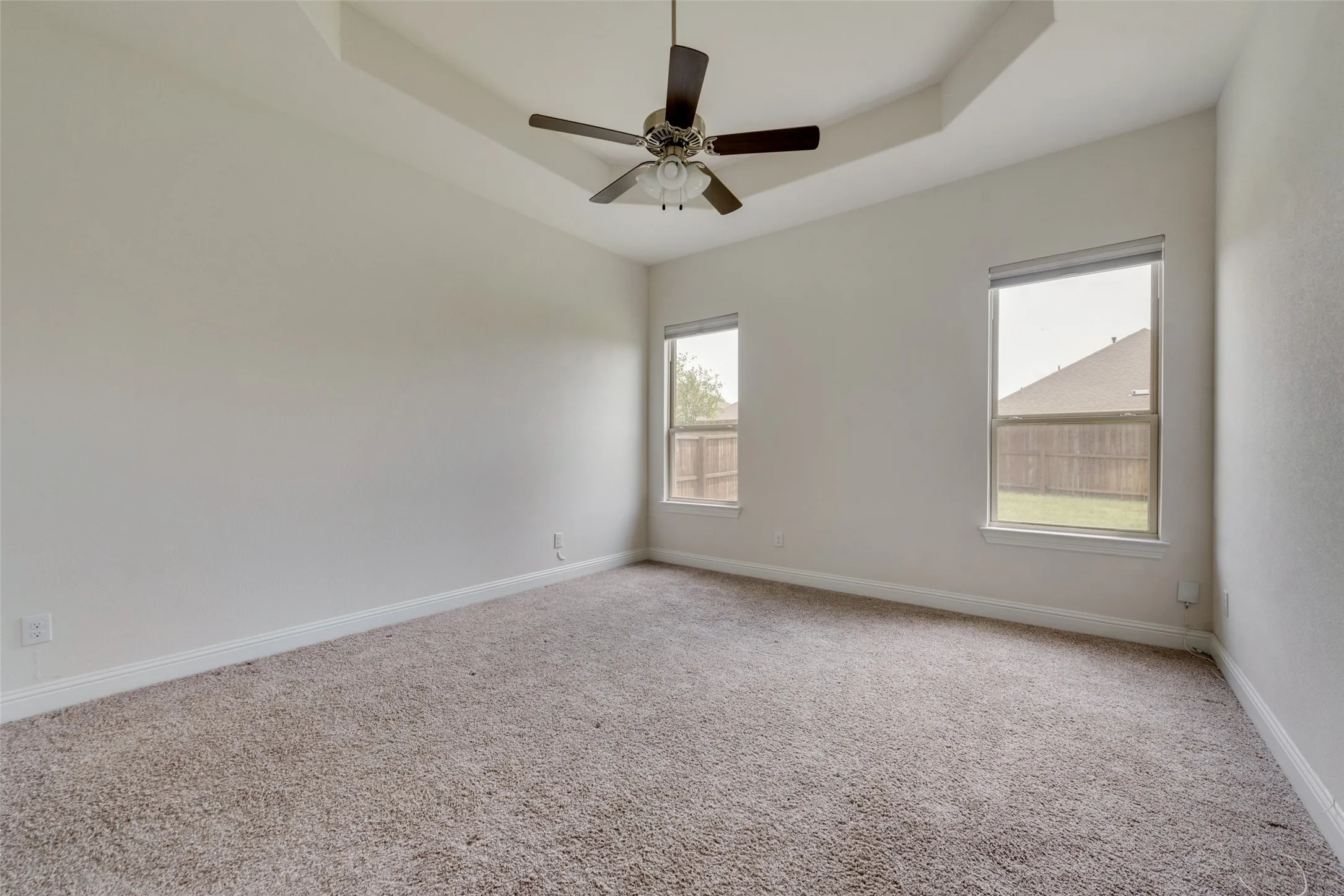 Carpeted empty room with a tray ceiling and ceiling fan