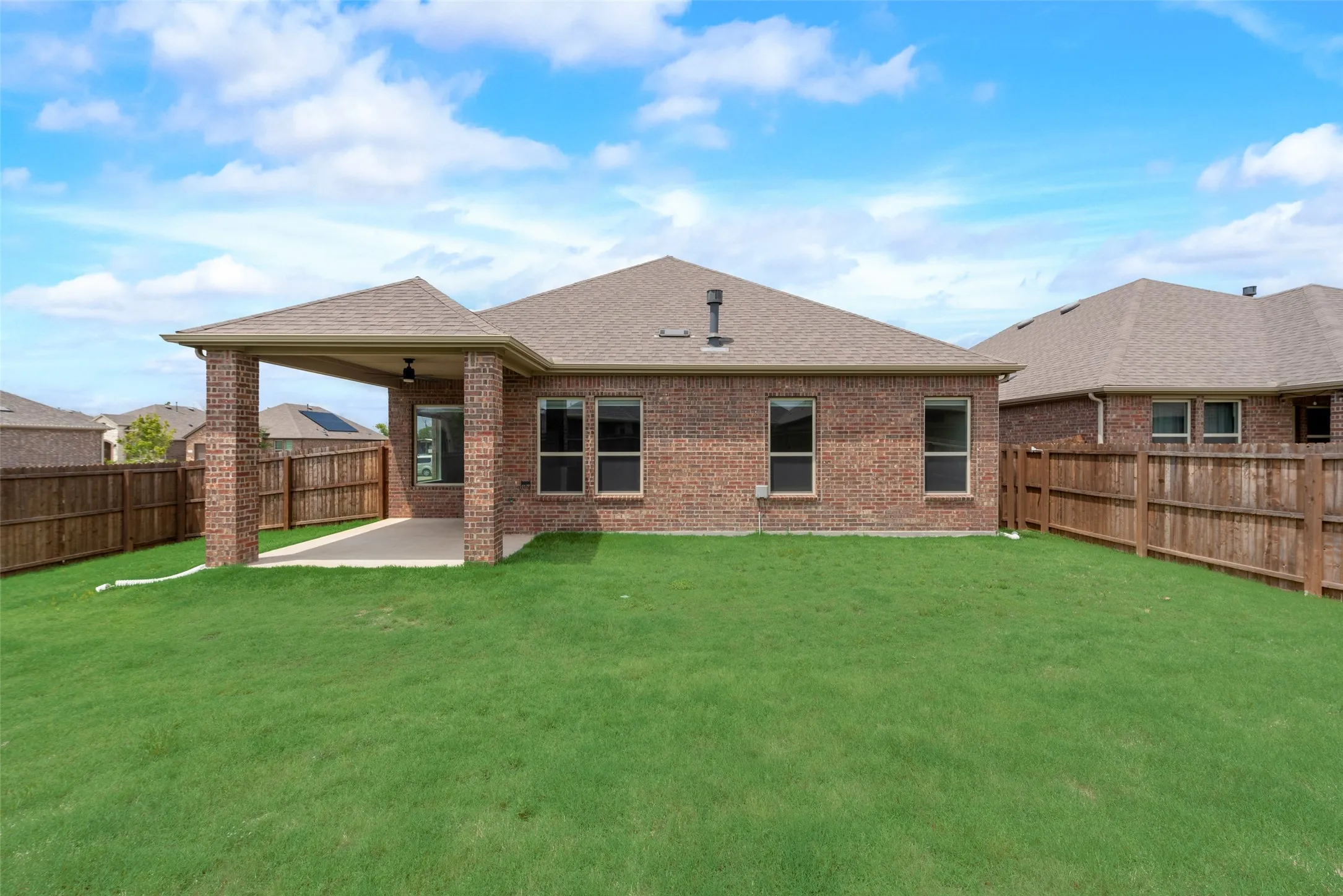 Rear view of property featuring a lawn and a patio area
