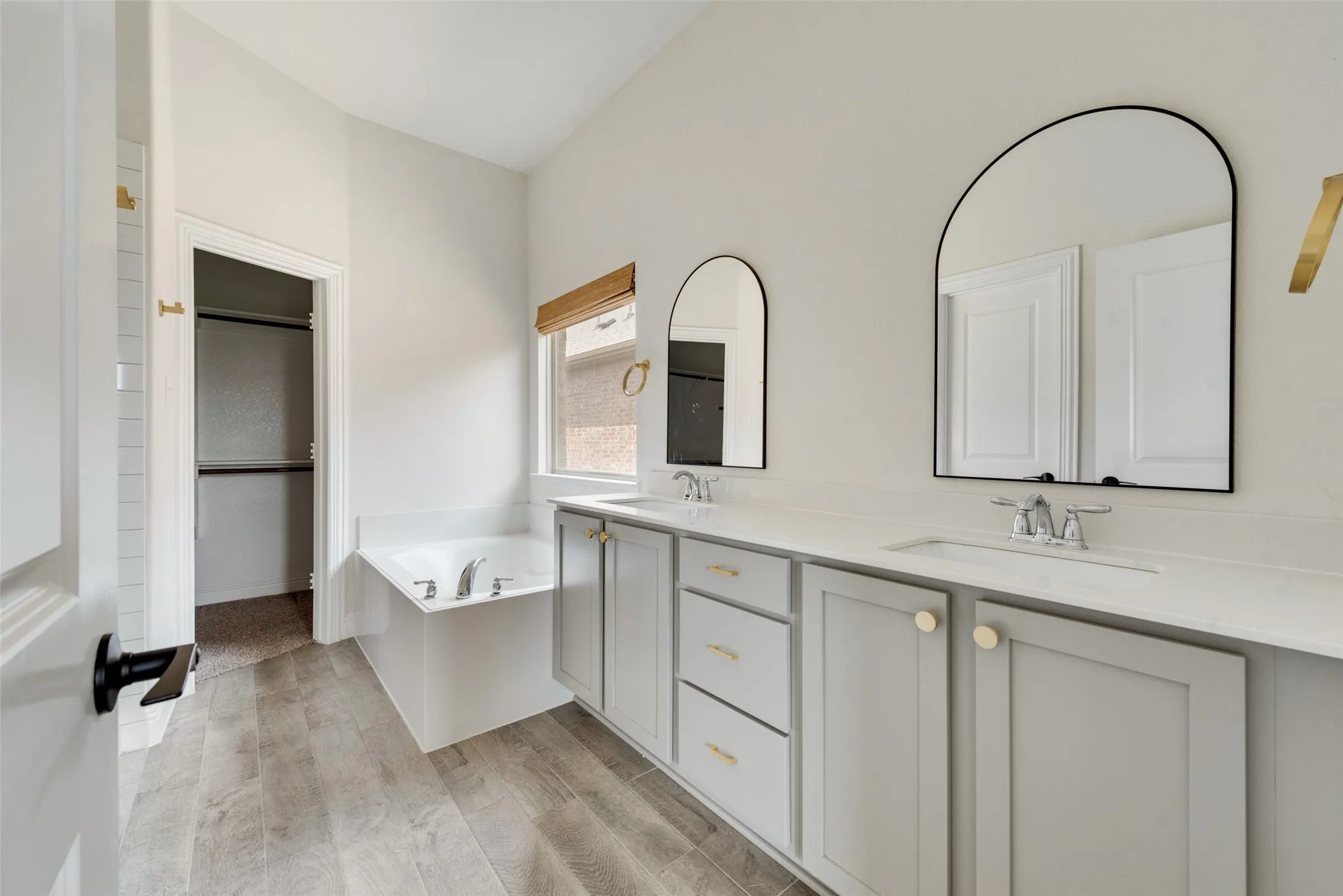 Bathroom with dual vanity, a washtub, and hardwood / wood-style flooring