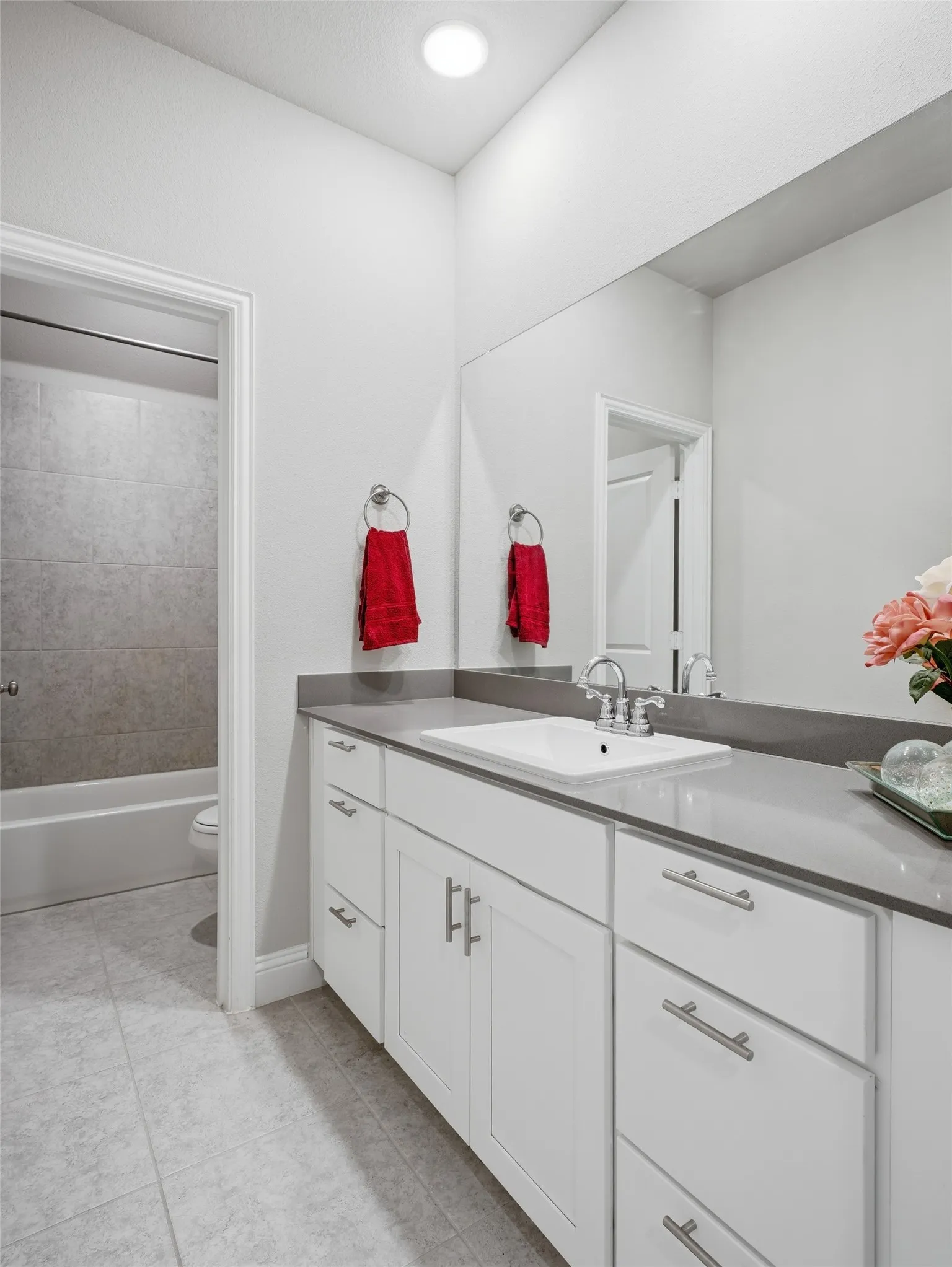 White shaker cabinetry with brushed nickel hardware, a single basin sink, and a gray countertop