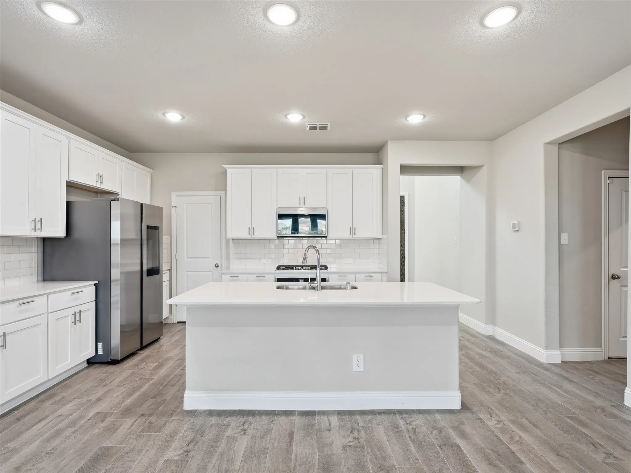 Kitchen featuring wood-finish flooring, white cabinetry, a central island, and stainless steel appliances