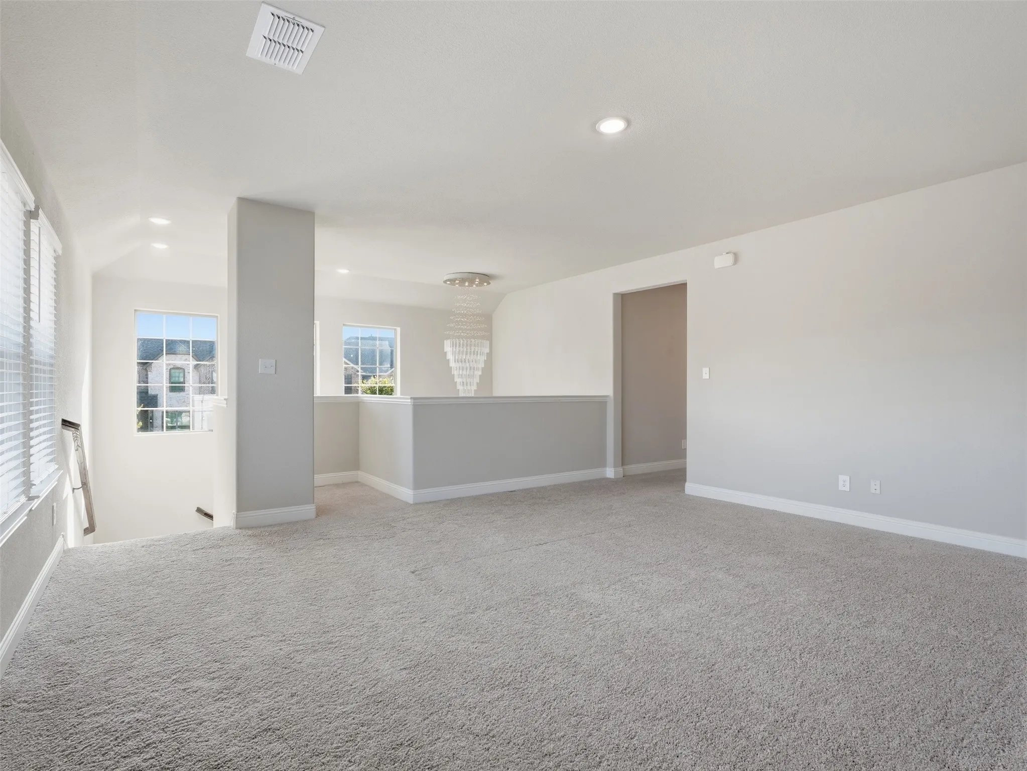 Carpeted upper level with recessed lighting, multiple windows, and a decorative chandelier